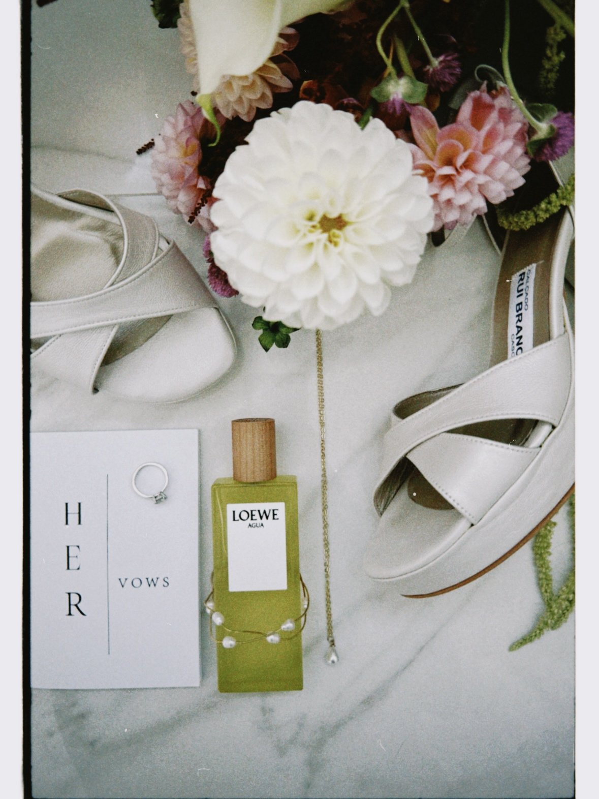 acessórios da noiva, como sapatos, bouquet, perfume, pulseira e o bloco onde estavam escritos os votos