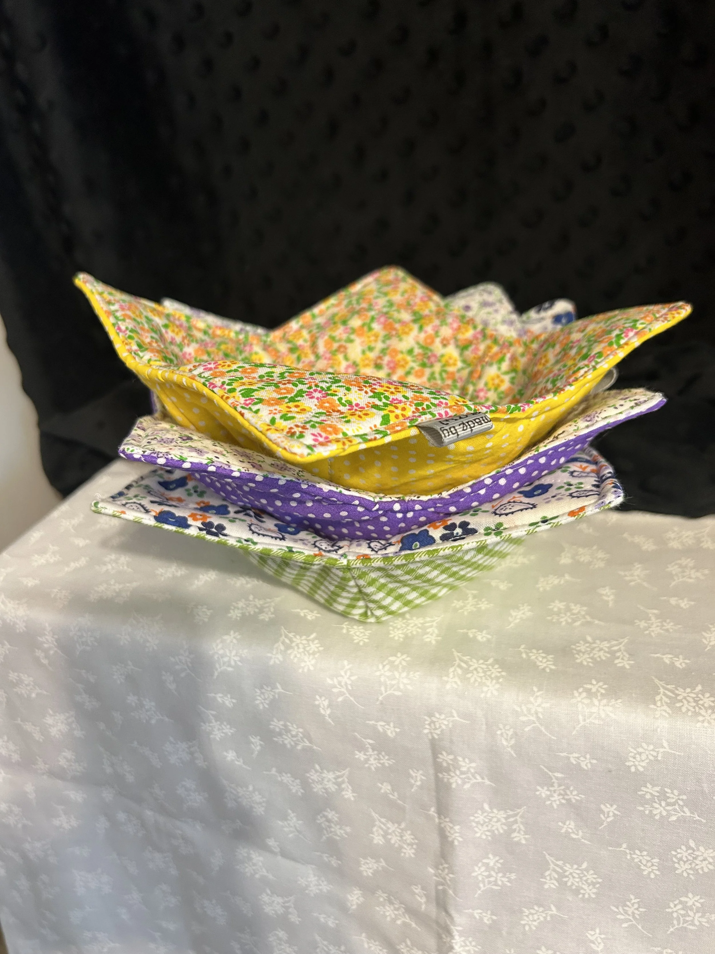 Stack of colorful floral and patterned cloth napkins on white tablecloth