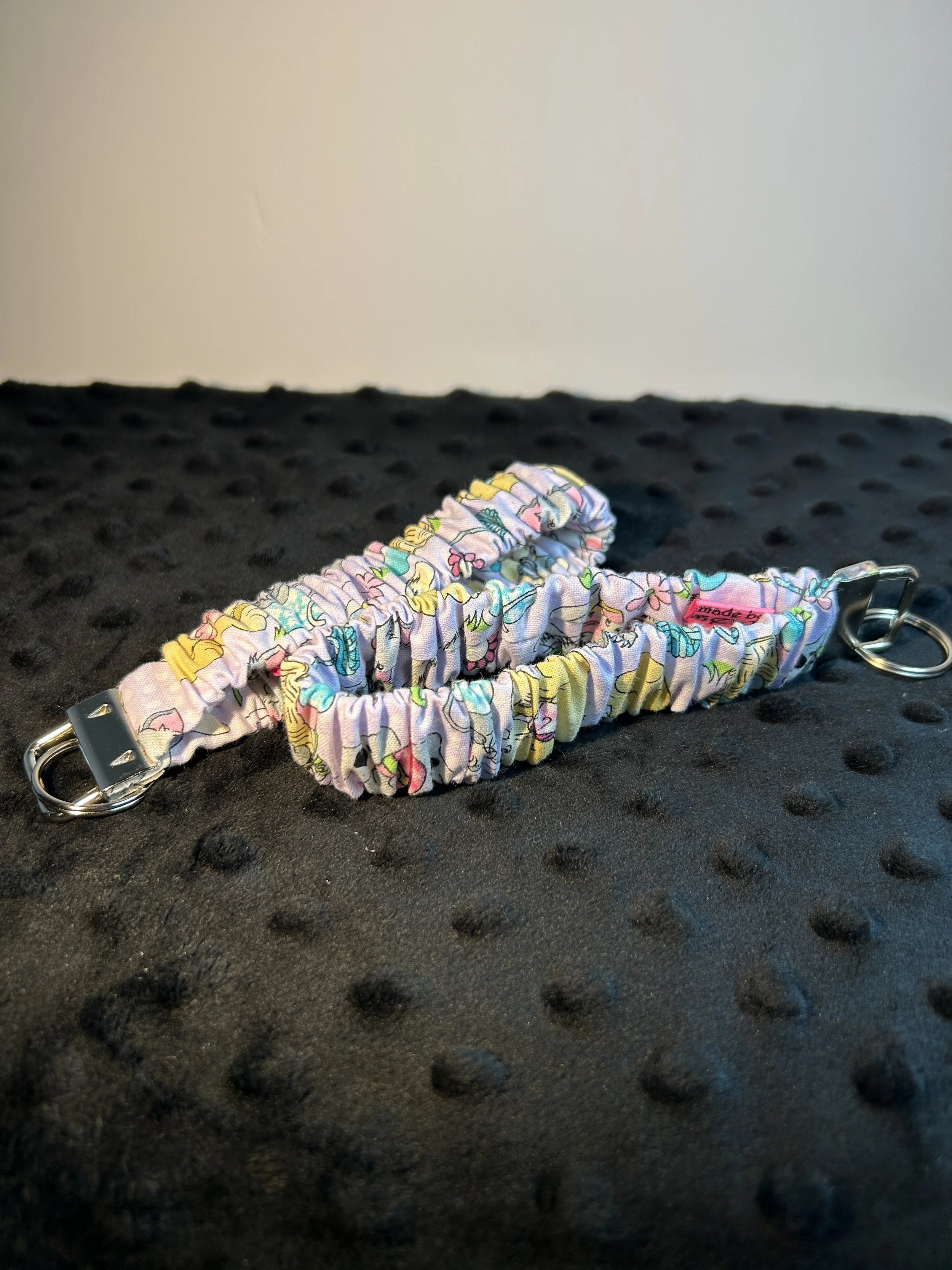 Colorful fabric sewn together and scrunched over sturdy elastic and secured to a metal clasp that can hold your keys it easily slides up your arm if you need to free up your hand great for gifts of any occasion