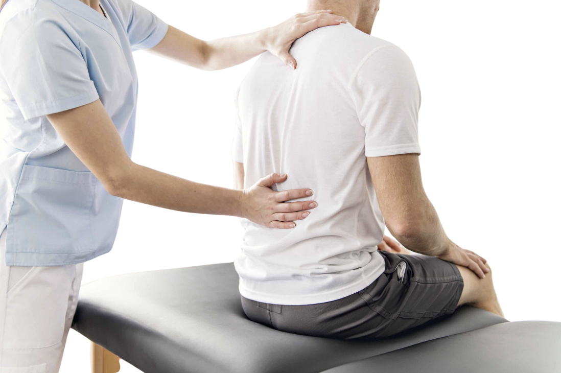 Healthcare professional examining a patient's back while seated on an examination table.