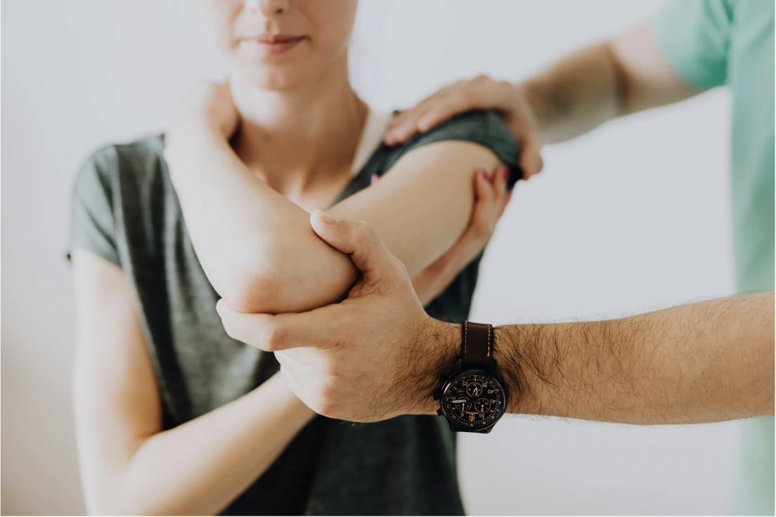 A healthcare professional examines a woman's arm during a medical consultation.