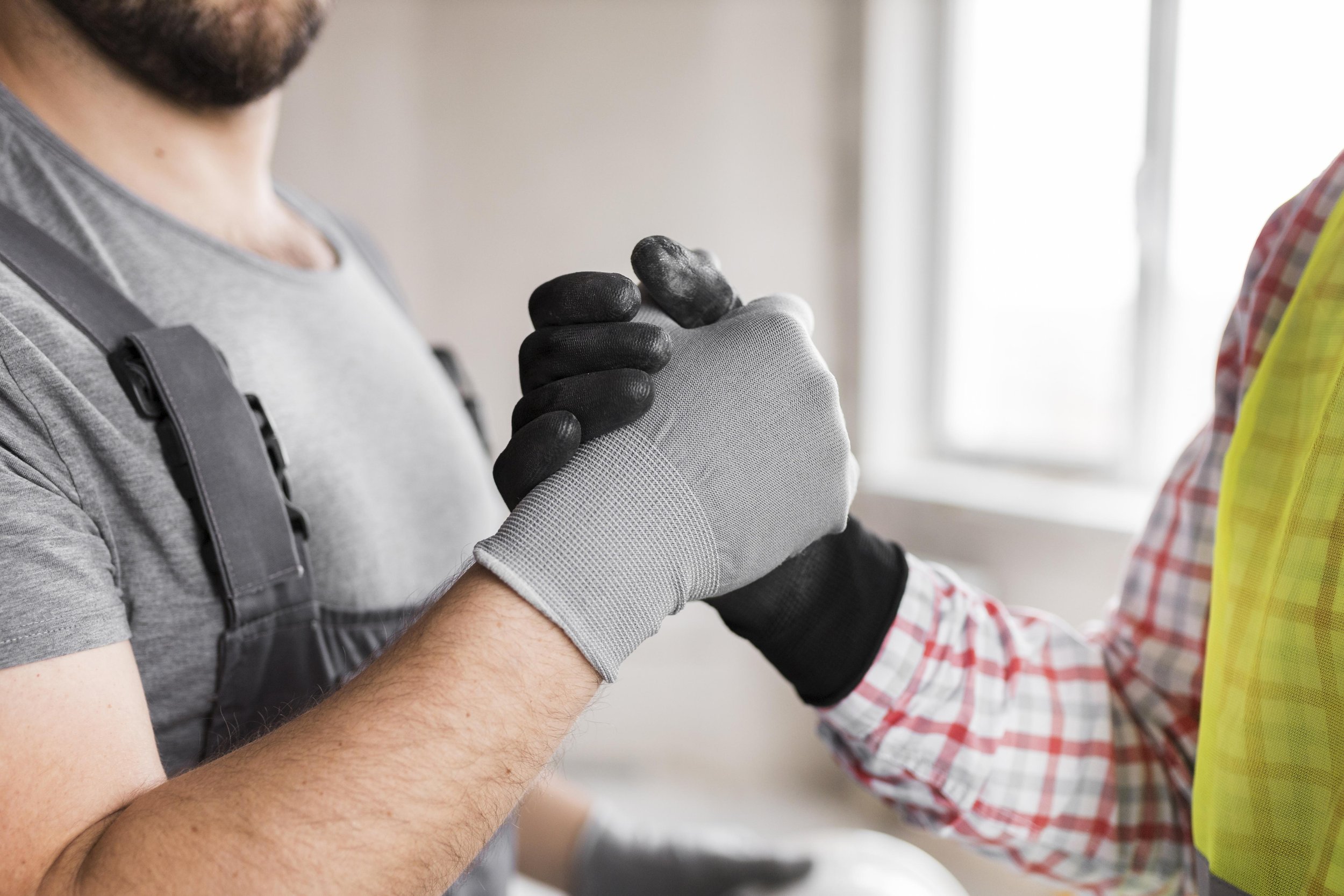 A person receiving a tattoo on their forearm from a tattoo artist. Both are wearing gloves, and the person being tattooed is holding their hand up.