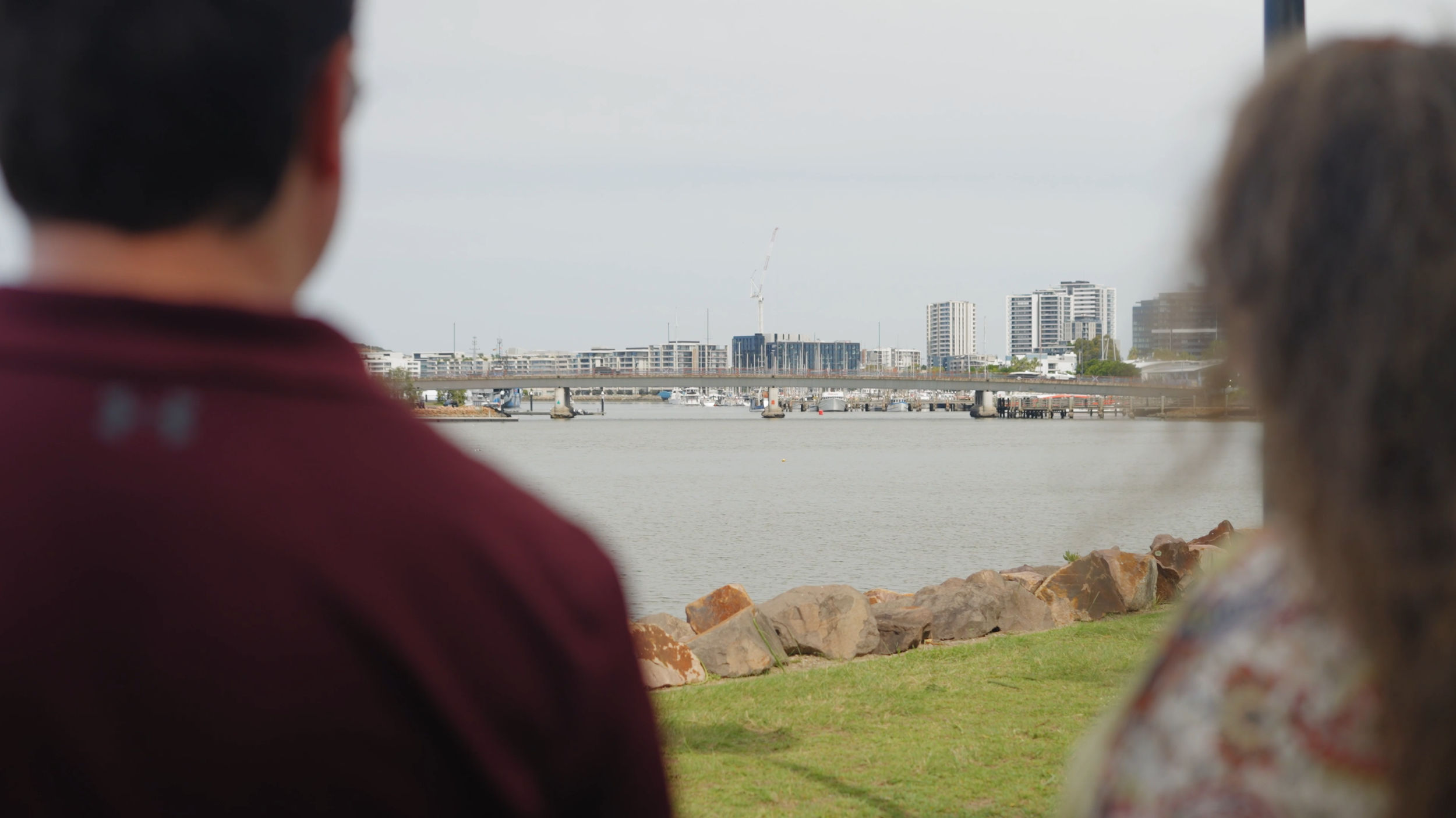 Michelle from Newcastle Social Workers sitting with an NDIS participant by the water, with the Newcastle foreshore in the distance, reflecting local and person-centred support coordination.