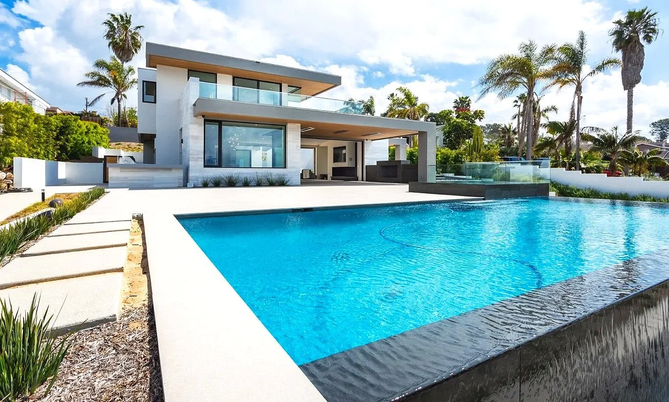 Modern house with large swimming pool and palm trees in backyard.