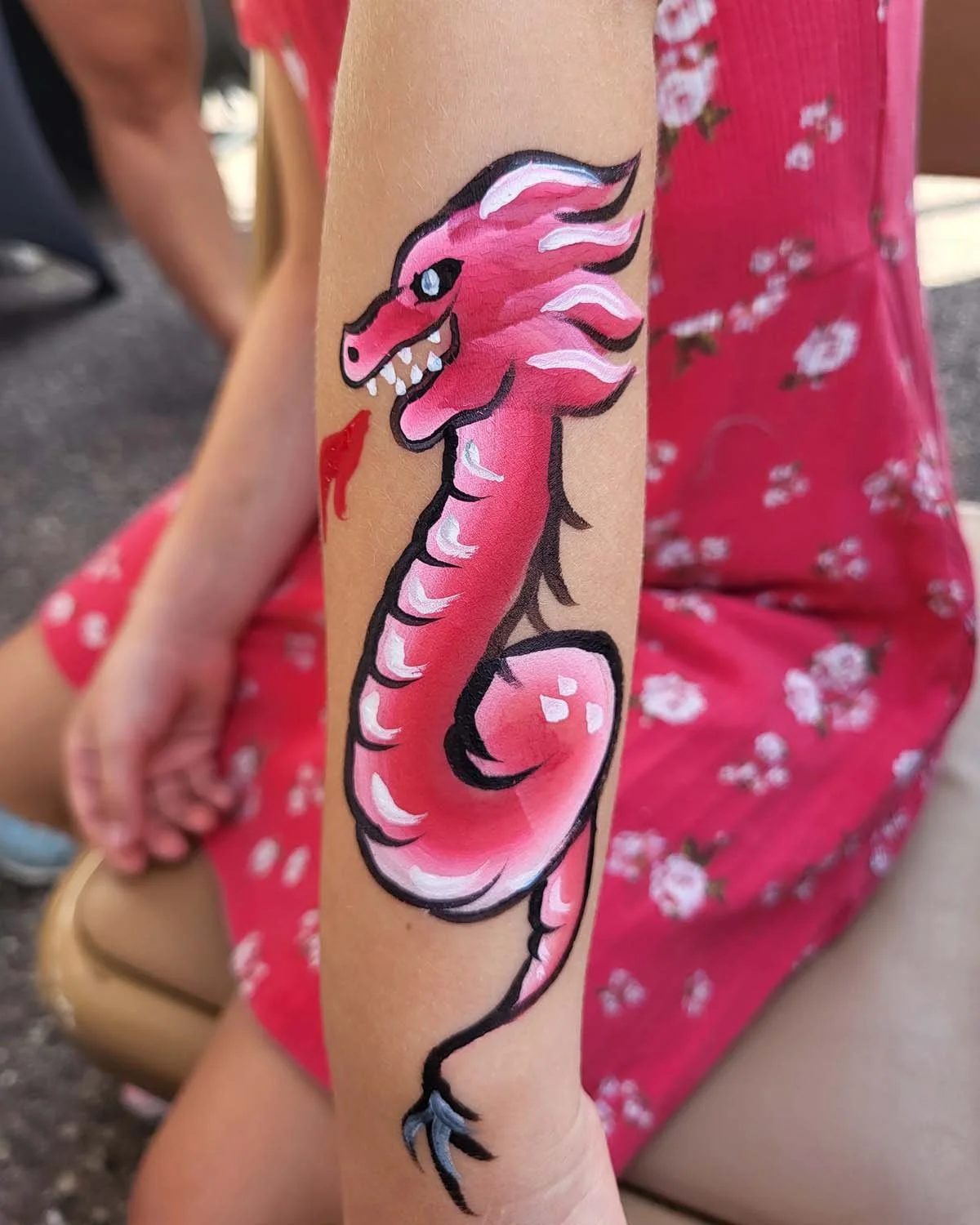 A cute pink dragon face painting in madison wi by witty kitty face painter