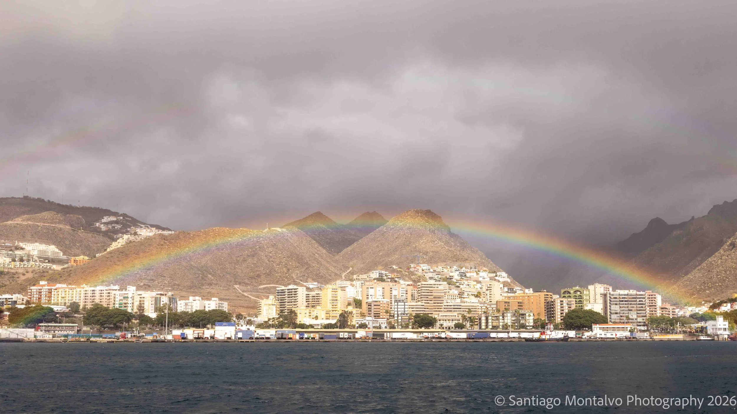 After the Storm — Tenerife, Canary Islands, Spain. A brilliant rainbow emerges above the coast beneath dramatic storm clouds.