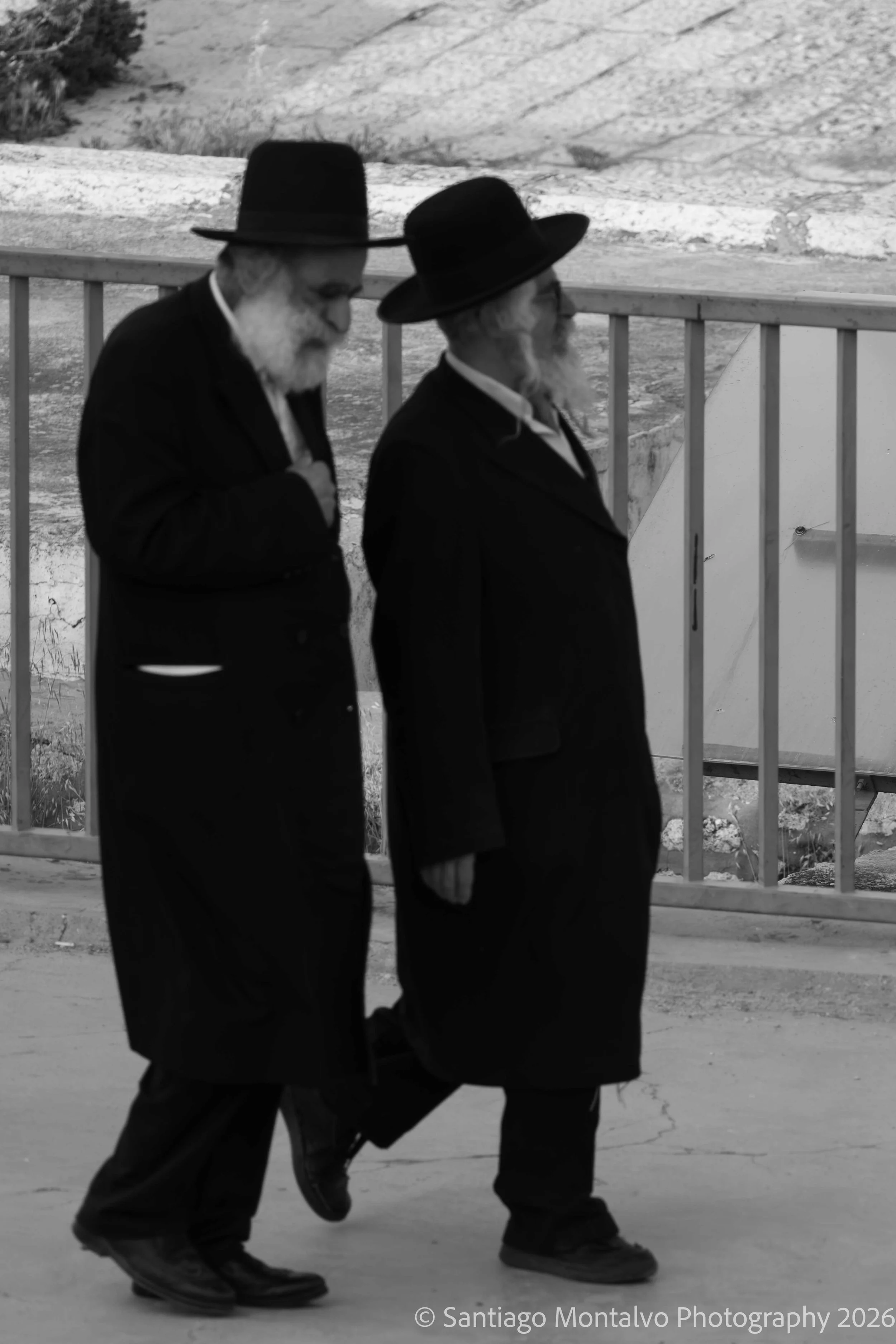 Walking Together — Jerusalem. Two figures share a quiet moment along a city street.
