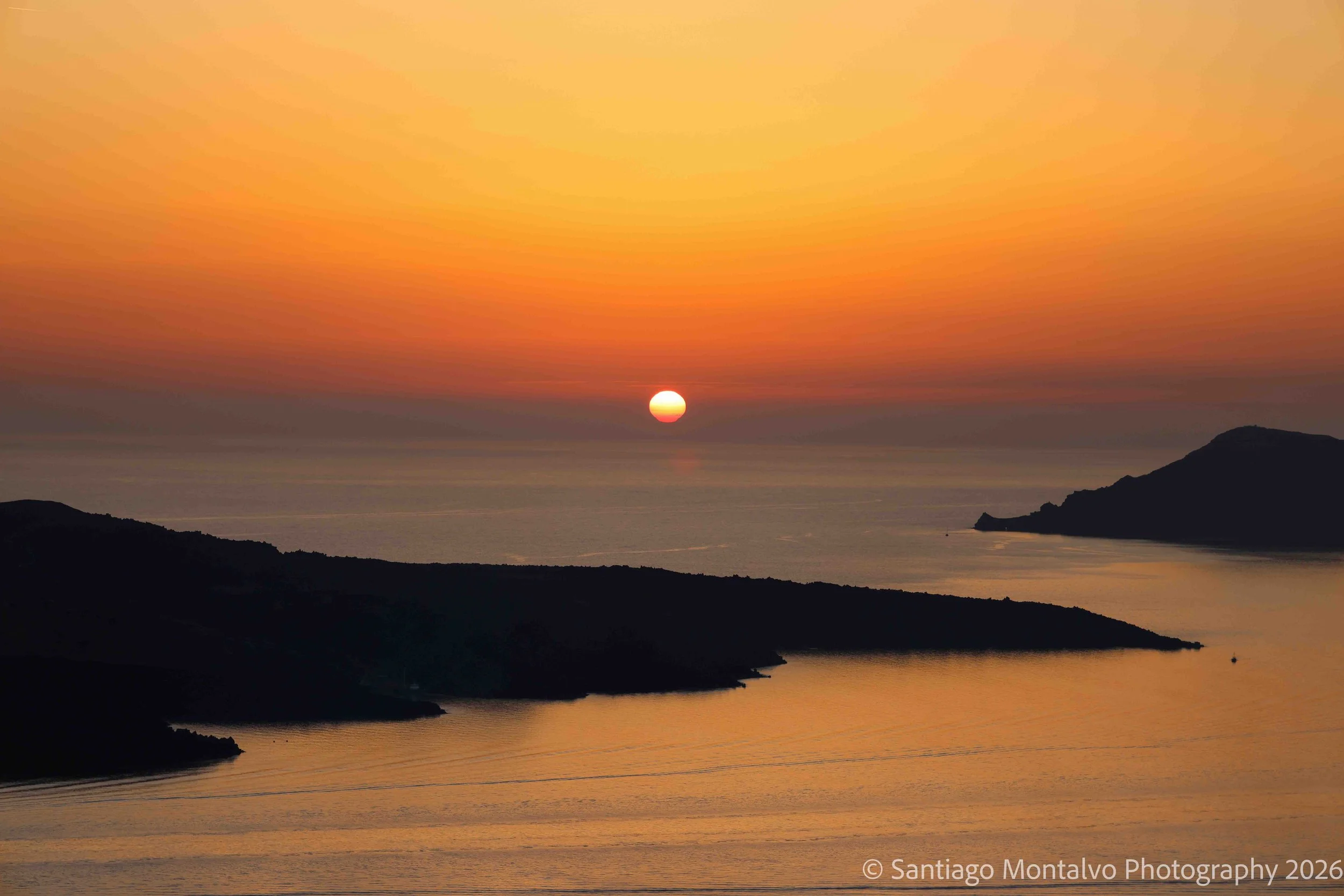 The Final Glow — Santorini, Greece. The sun meets the horizon in a luminous farewell to the day.