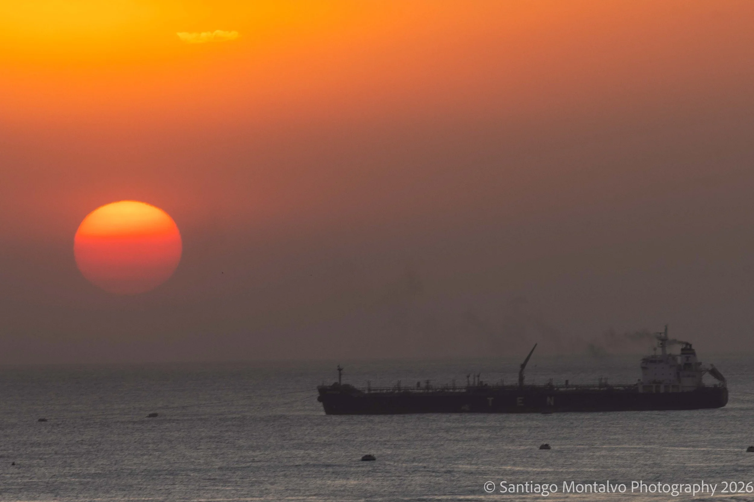 Sunset Passage — Guatemala. A brilliant setting sun and the silhouette of a distant vessel create an unforgettable horizon.