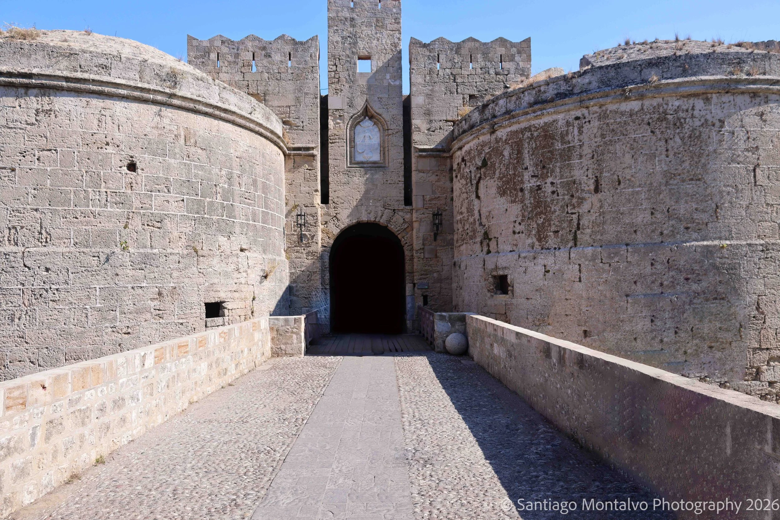 The Medieval Gateway — Rhodes, Greece. Sunlit stone and deep shadow frame an entrance into centuries of island history.
