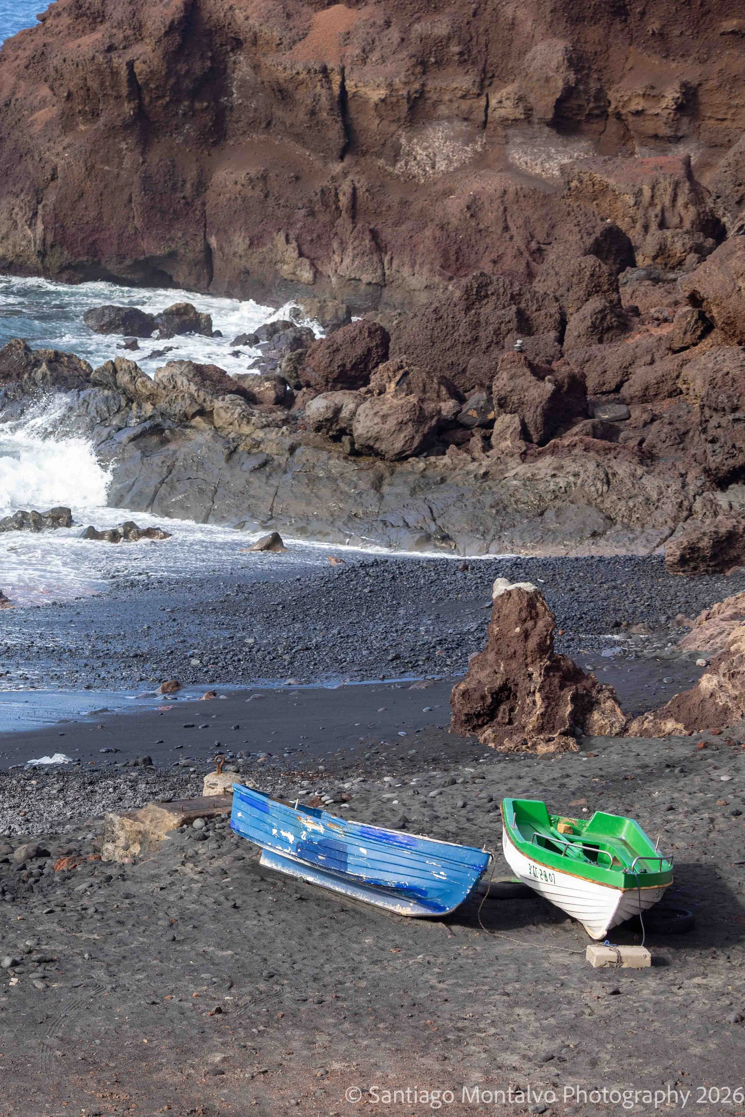 Boats on Black Sand — Lanzarote, Spain. Colorful fishing boats rest against a volcanic shoreline.