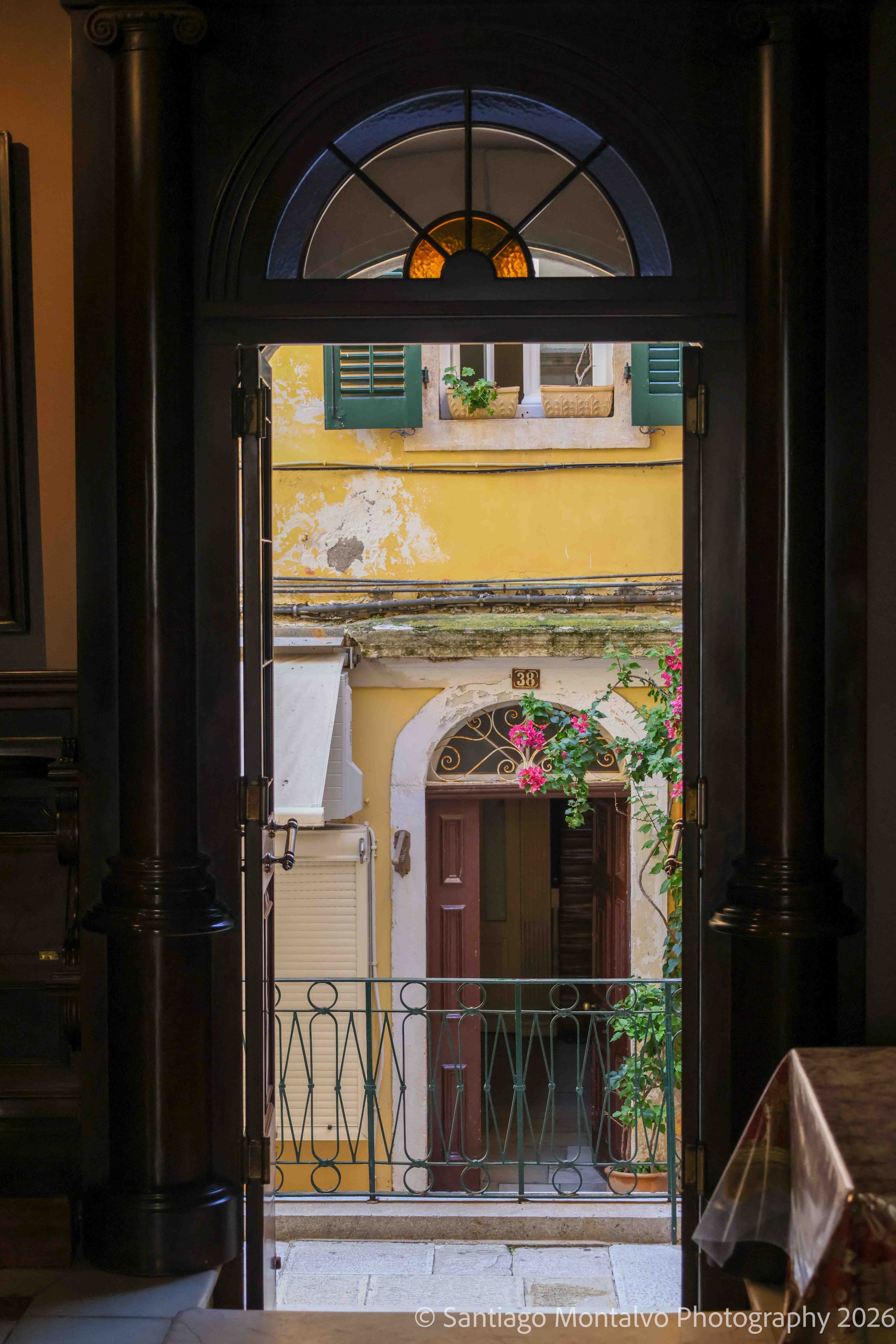 A Colorful Passage — Corfu, Greece. Bright flowers, pastel walls, and traditional shutters reveal the charm of a Mediterranean street.