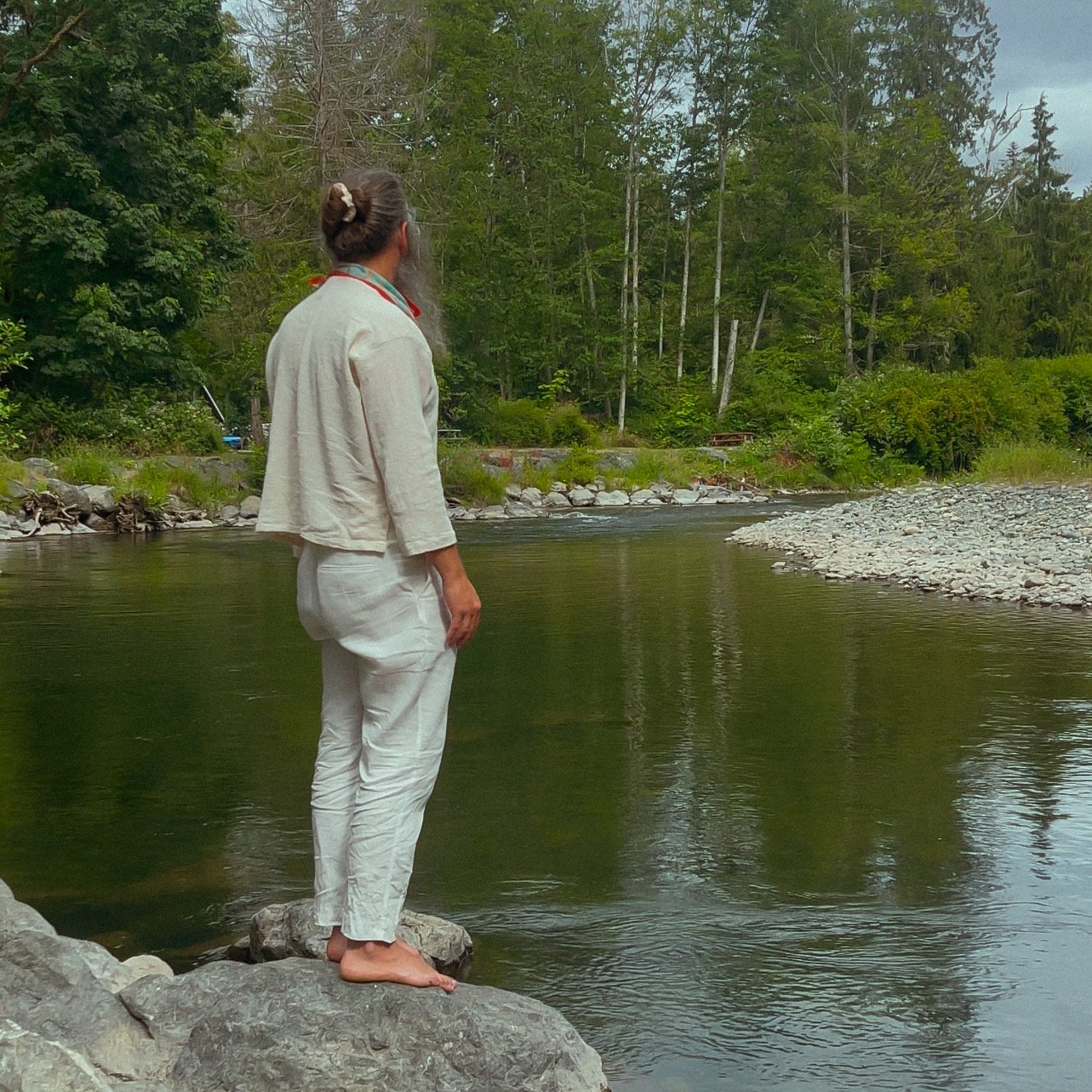 Muni Engel, dressed in traditional white linens, practicing mindfulness by the river—illustrating the path of a modern-day Muni.