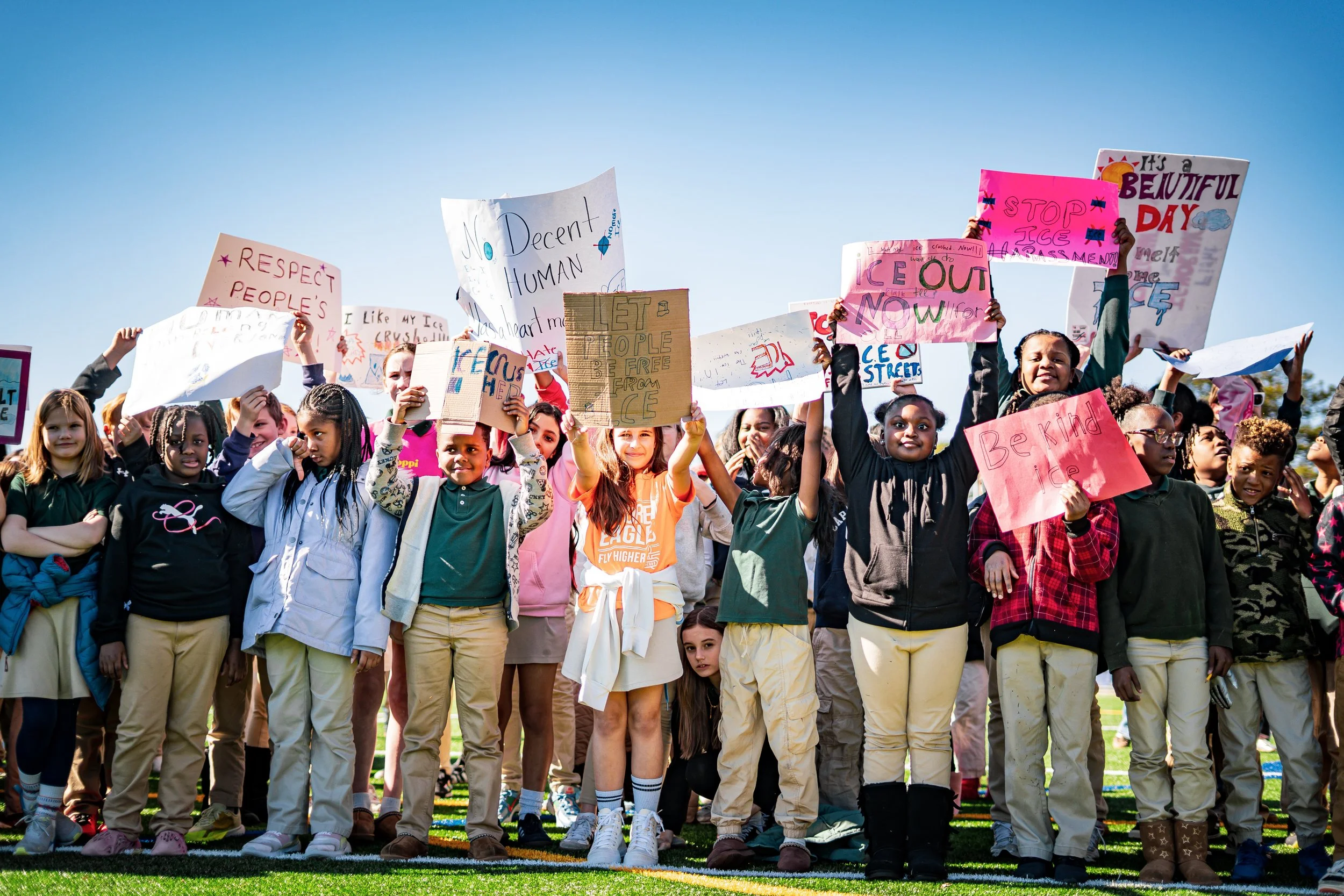 Group of children protesting outdoors, holding signs with messages promoting kindness, respect, and climate awareness.