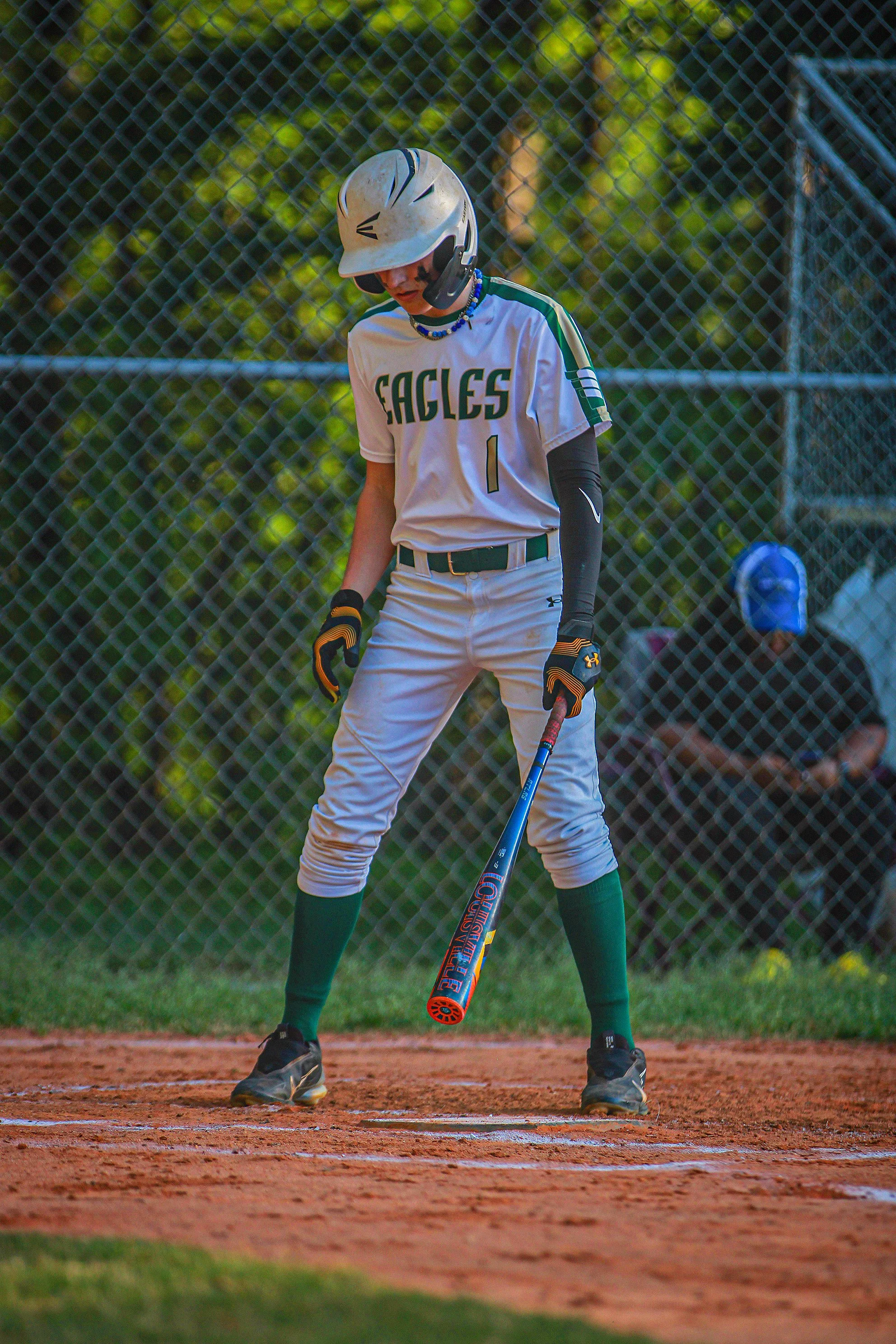A baseball player wearing a uniform with 'EAGLES' on it, standing on a dirt base path with a bat in hand, ready for batting.