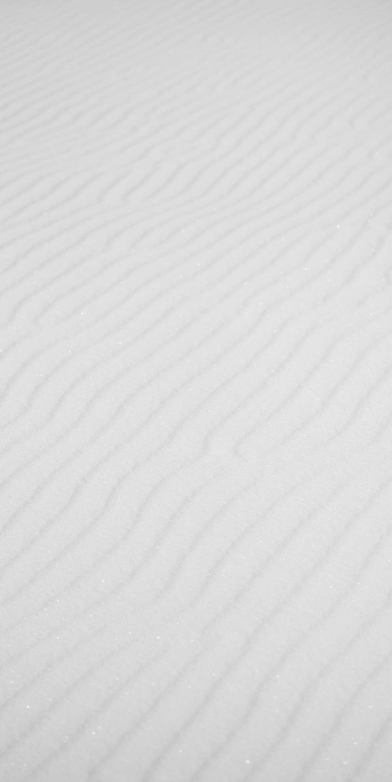 Close-up of wind-blown snow with visible ridges.