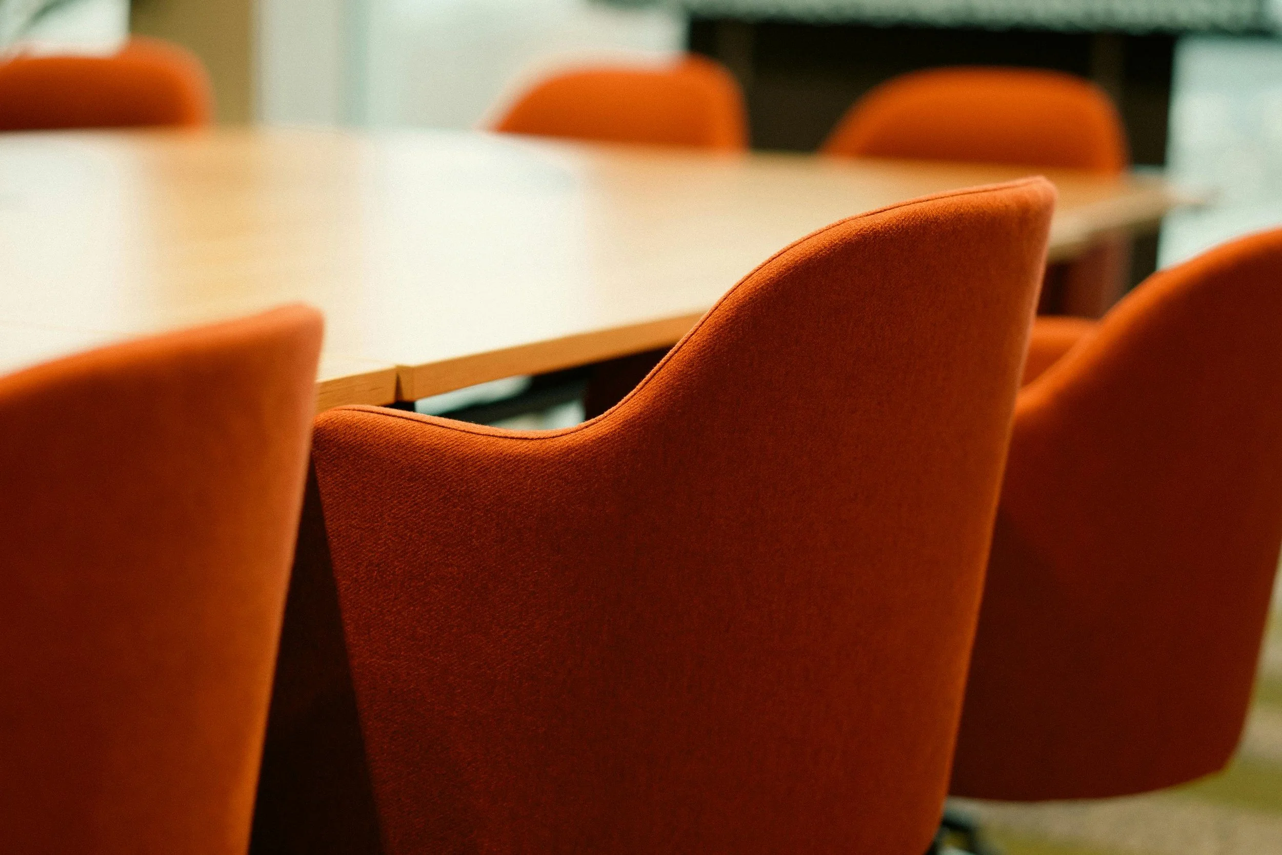 Empty conference room with orange chairs around a wooden table.