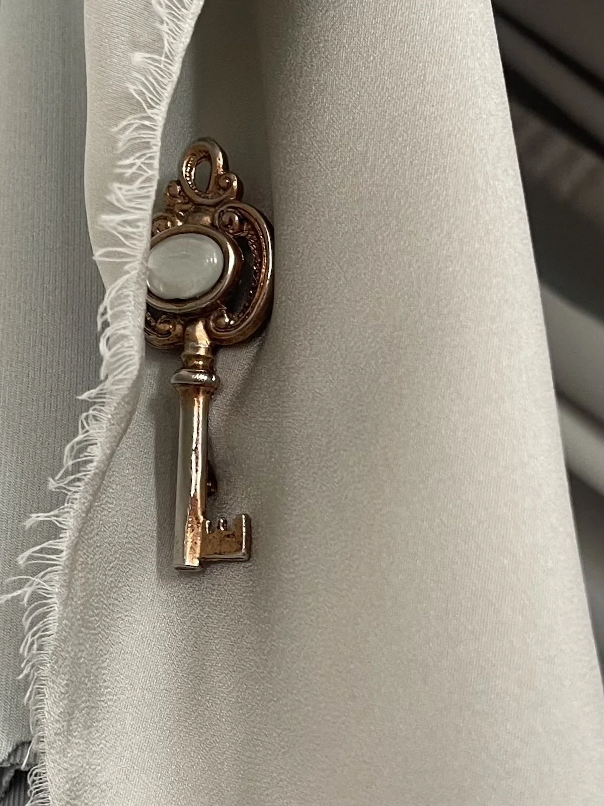 A vintage-style key with a decorative bow resting on a gray fabric surface.