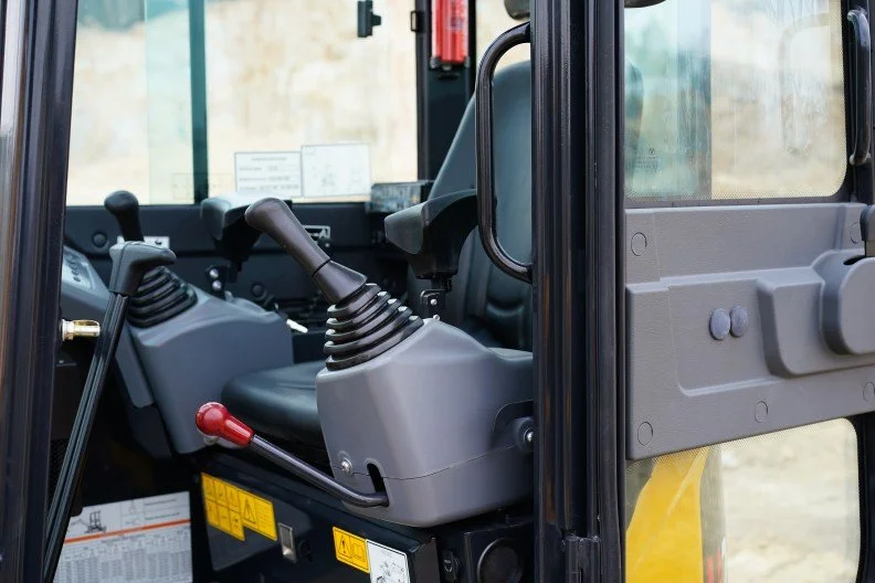Interior of a construction or industrial vehicle with control levers and a steering wheel.