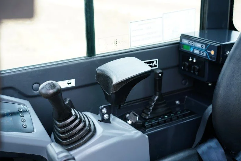 Inside a bus cockpit showing a steering wheel, gear shift, and control panel.