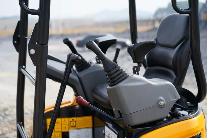 Close-up of the control panel and seat of a yellow construction vehicle, likely a mini excavator or skid-steer loader.
