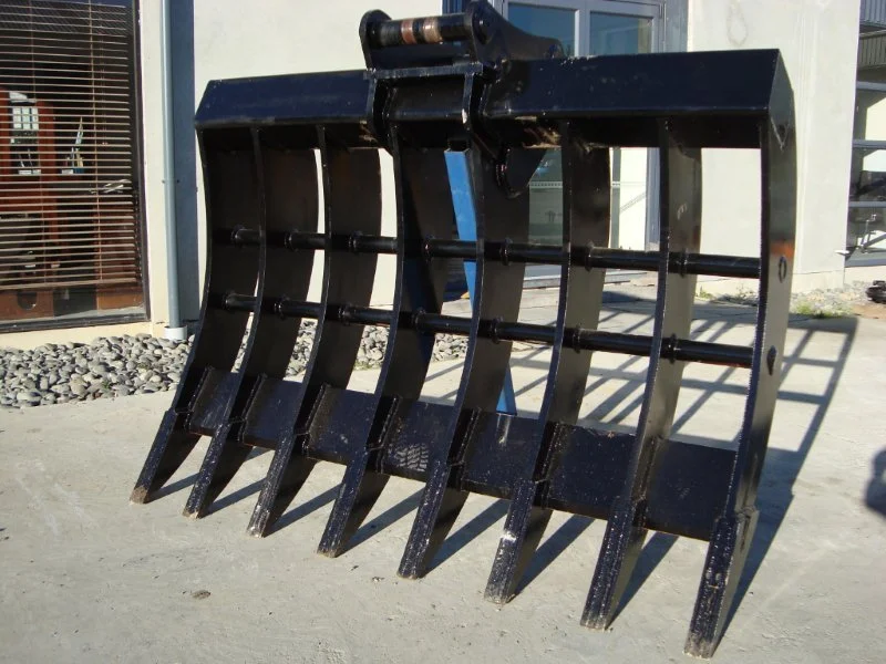 Heavy black excavation bucket attachment for a construction or tractor machine outdoors on concrete ground.