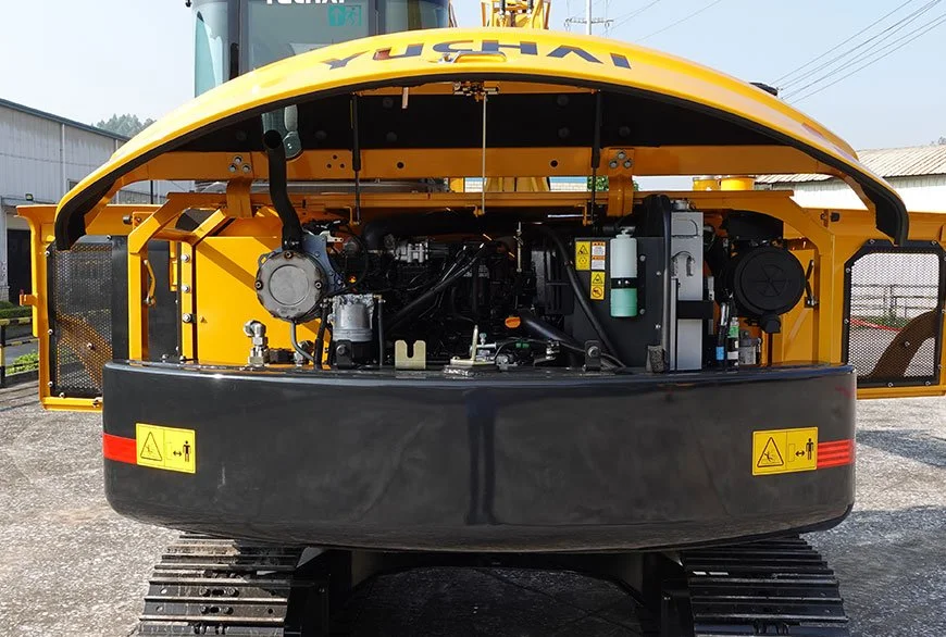 Front view of a yellow construction vehicle showing engine components and warning labels.