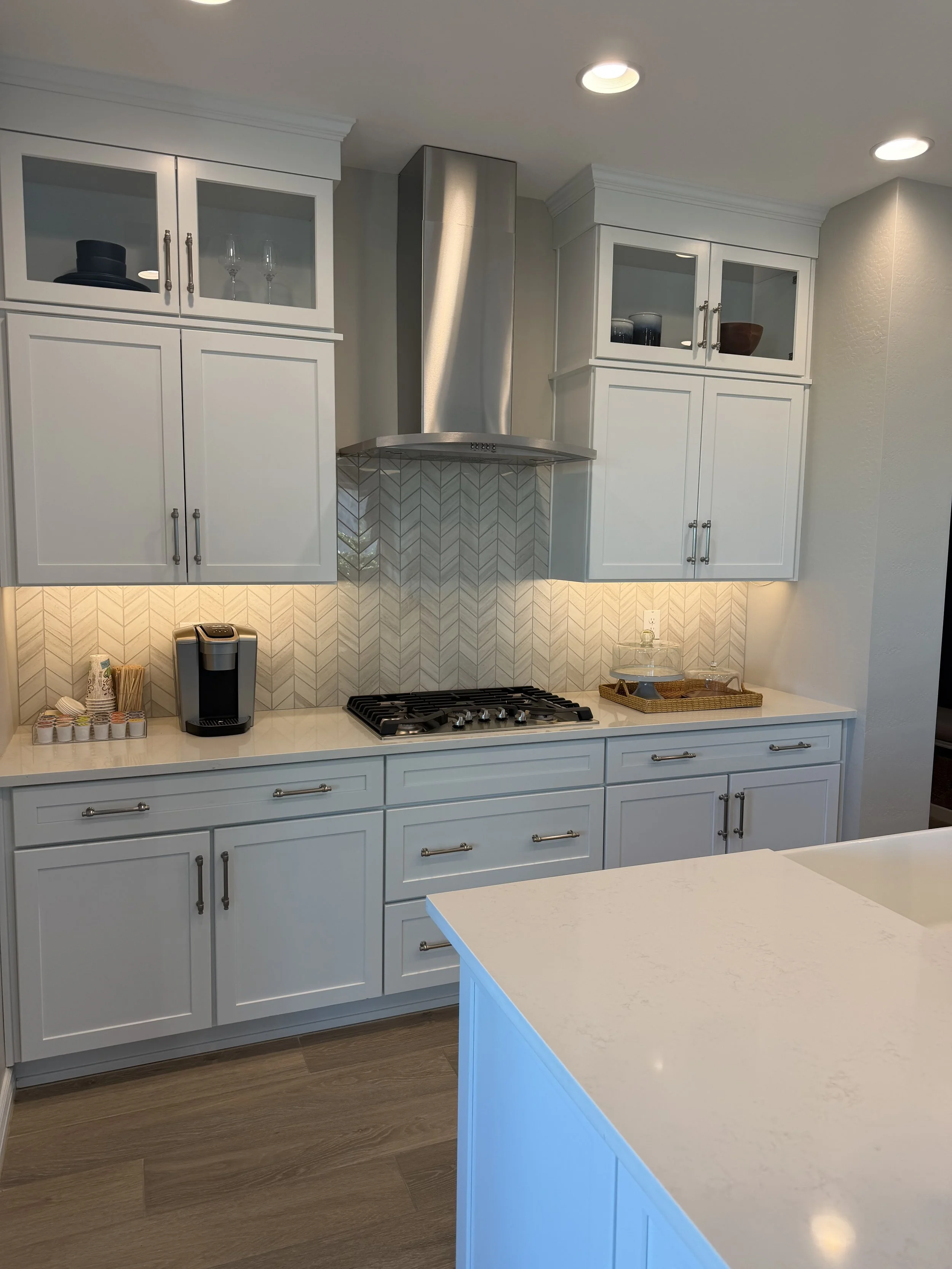 Kitchen with white cabinetry, a stovetop, countertop appliances, and a modern backsplash.