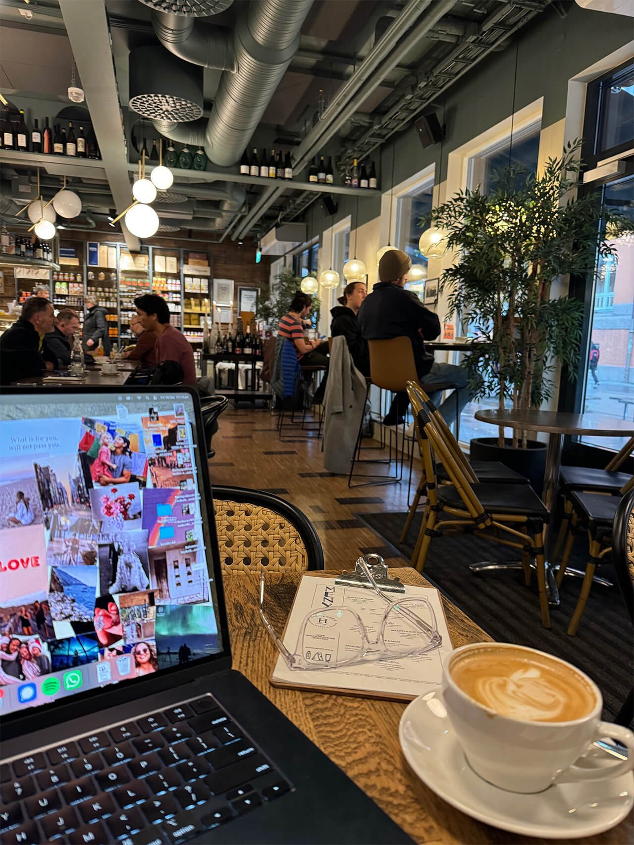 A busy café in Norway with Paige's laptop and coffee on a table in the foreground