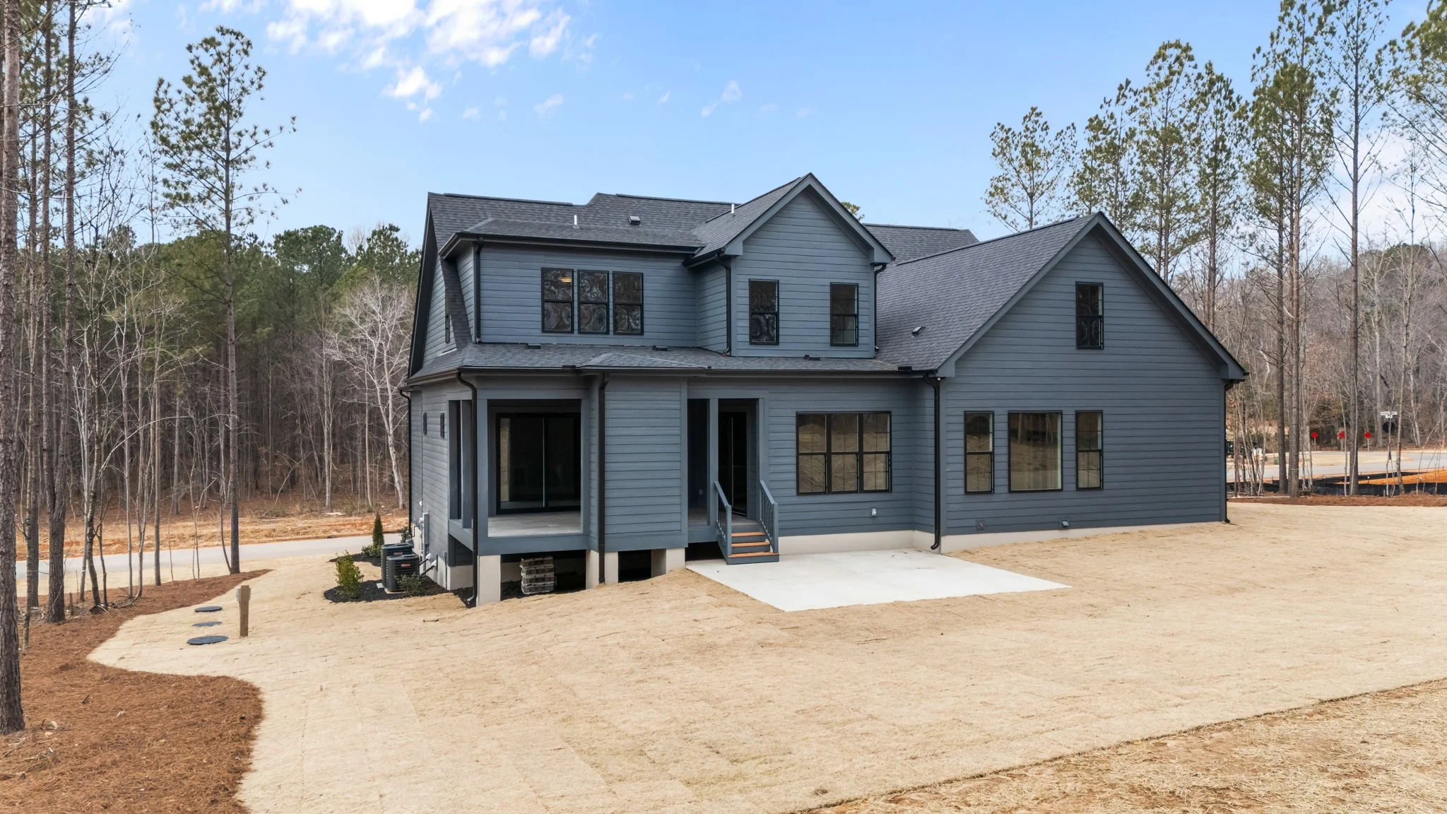 Back exterior of custom home with covered porch, outdoor fireplace, and sliding doors to backyard