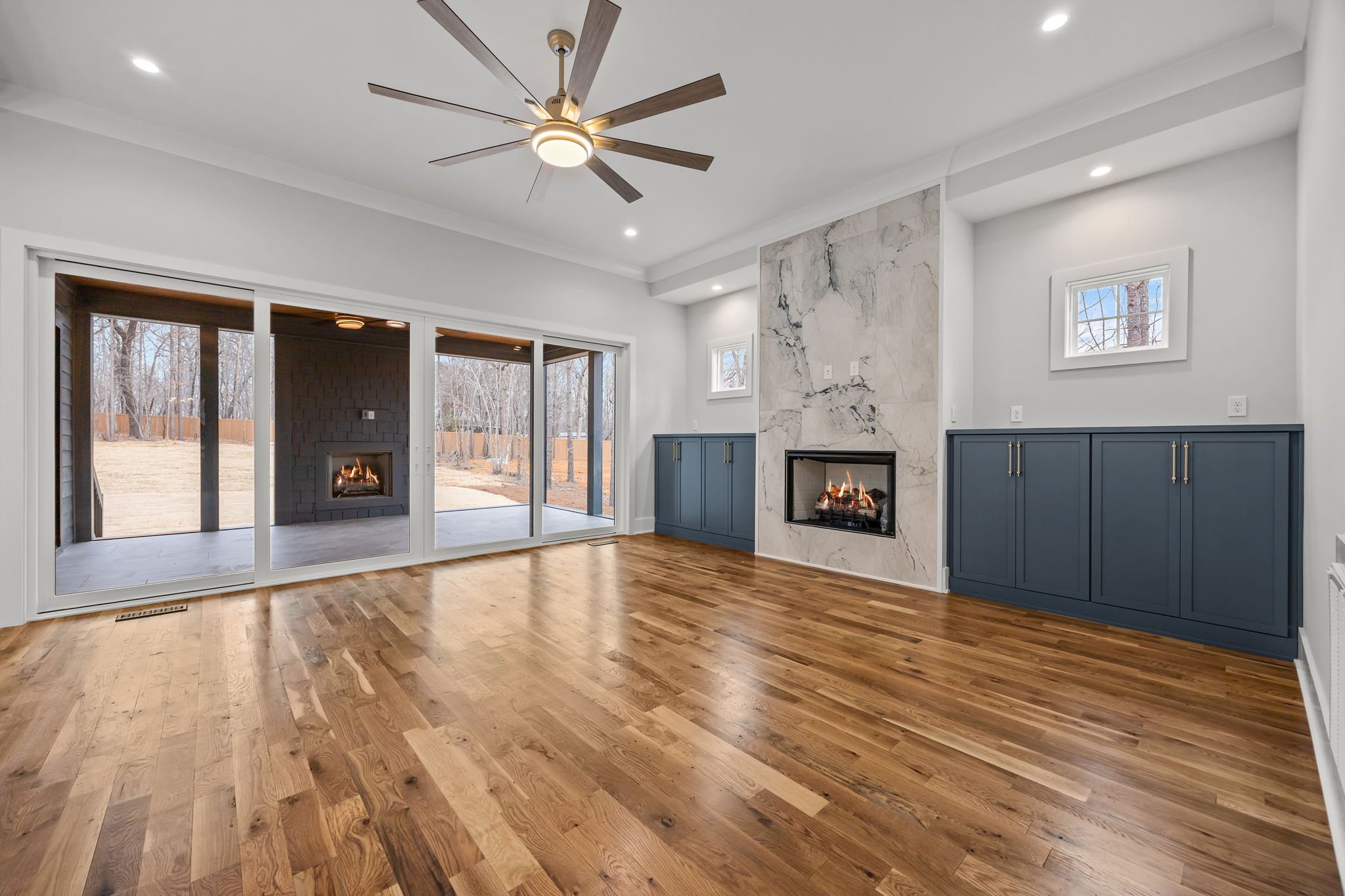 Open concept living room with fireplace, built-in shelving, and sliding glass doors leading to covered outdoor patio