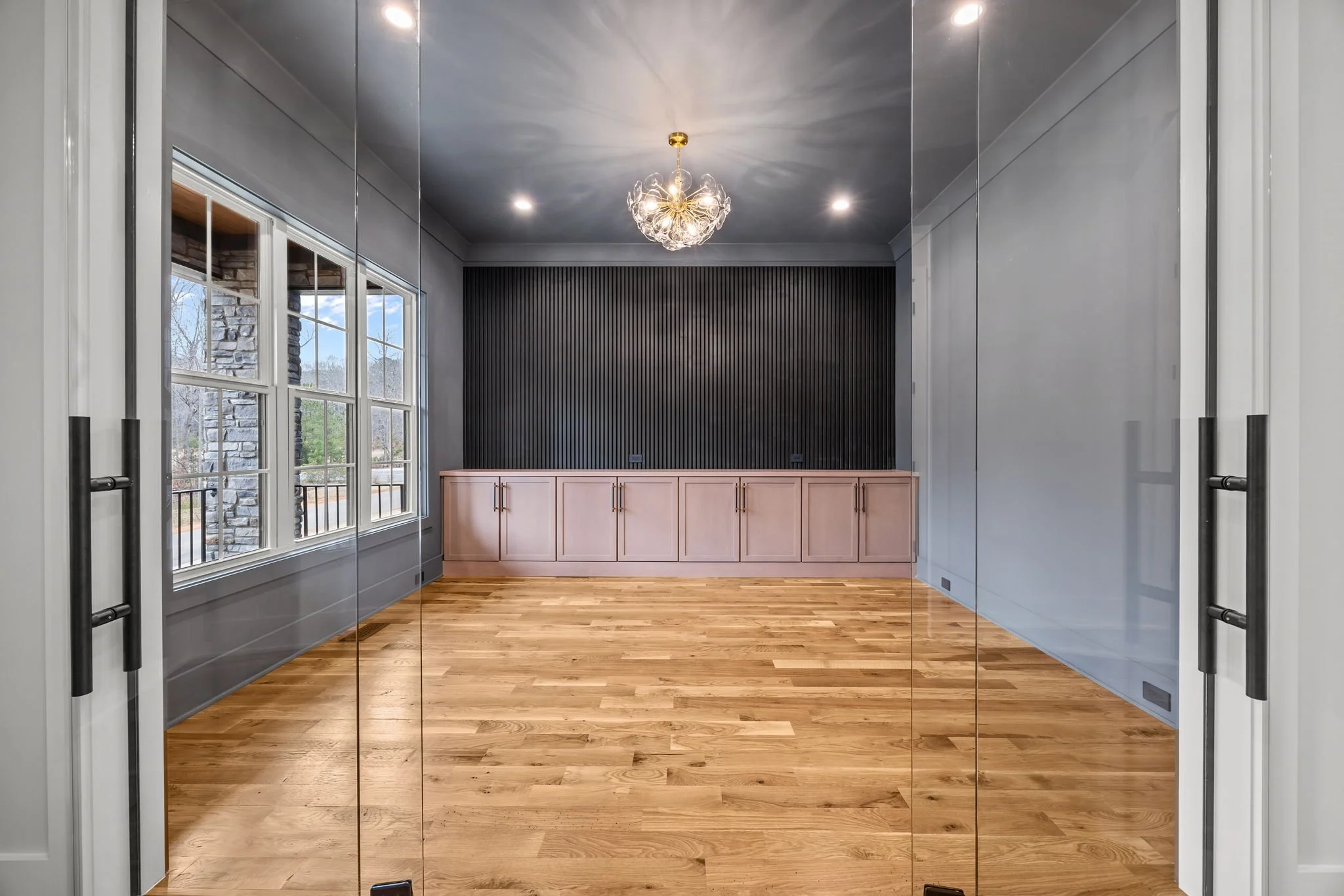 Interior room with black accent wall, built-in shelving, wall sconces, and chandelier lighting