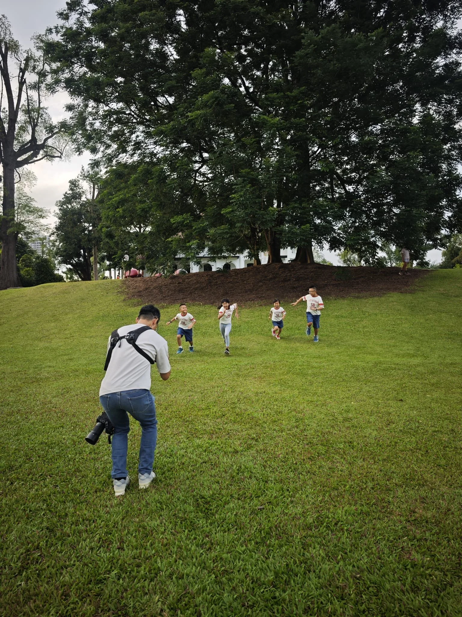 Behind the Scence shot of a family photographer taking photo of kids running down the slope.