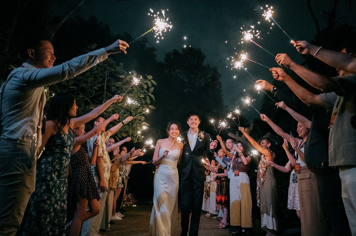 wedding couple walking down with a row of friends holding on to fire sparklers