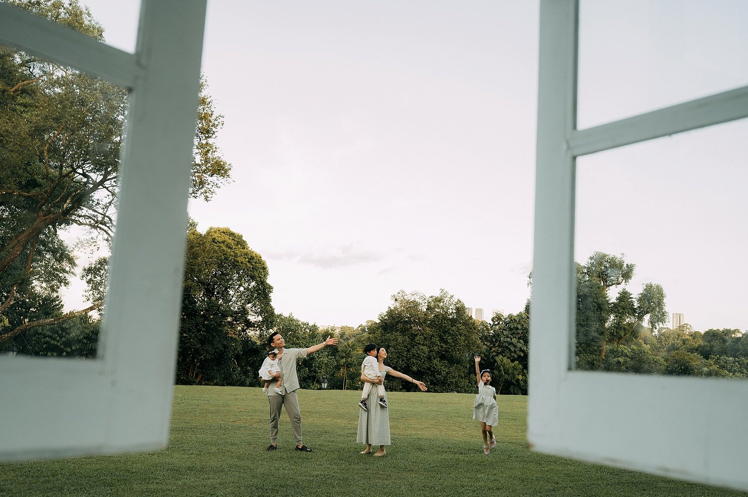 Natural family outdoor photoshoot in Singapore, using the modern architecture of the Gallop Extension window as the foreground