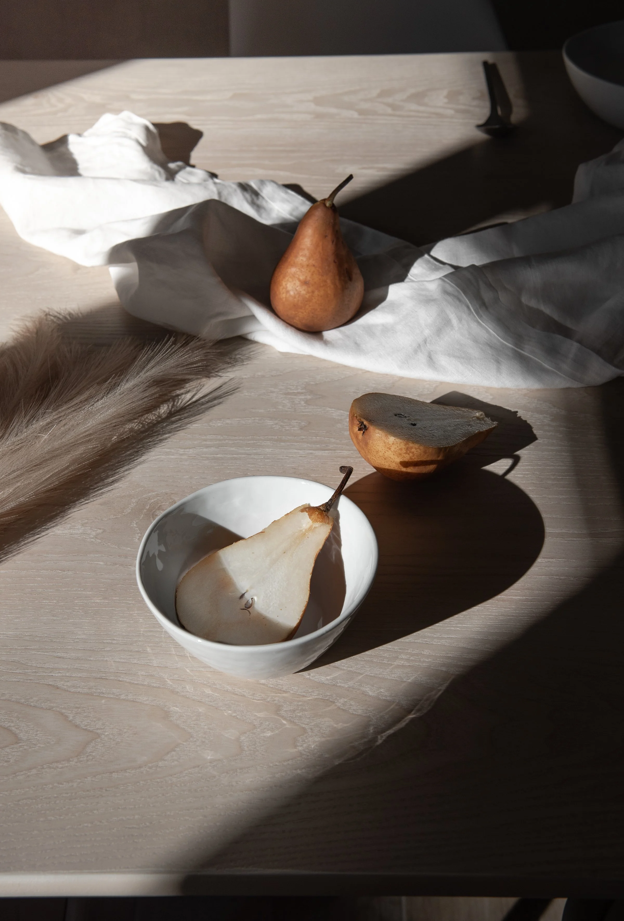 cut and whole pears on a table with a feather