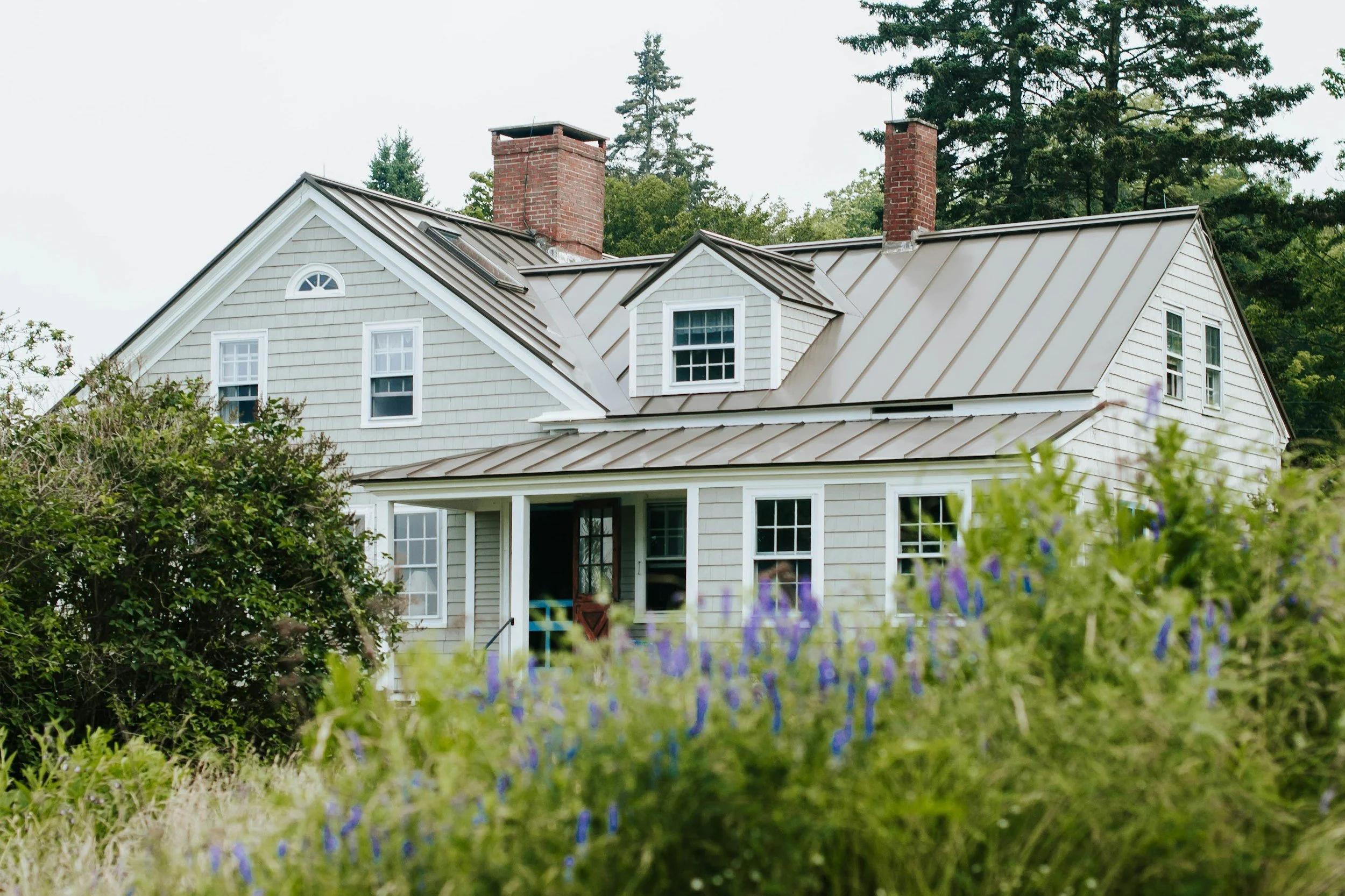 Northern Virginia home exterior with gables, metal roof, and flowering landscaping