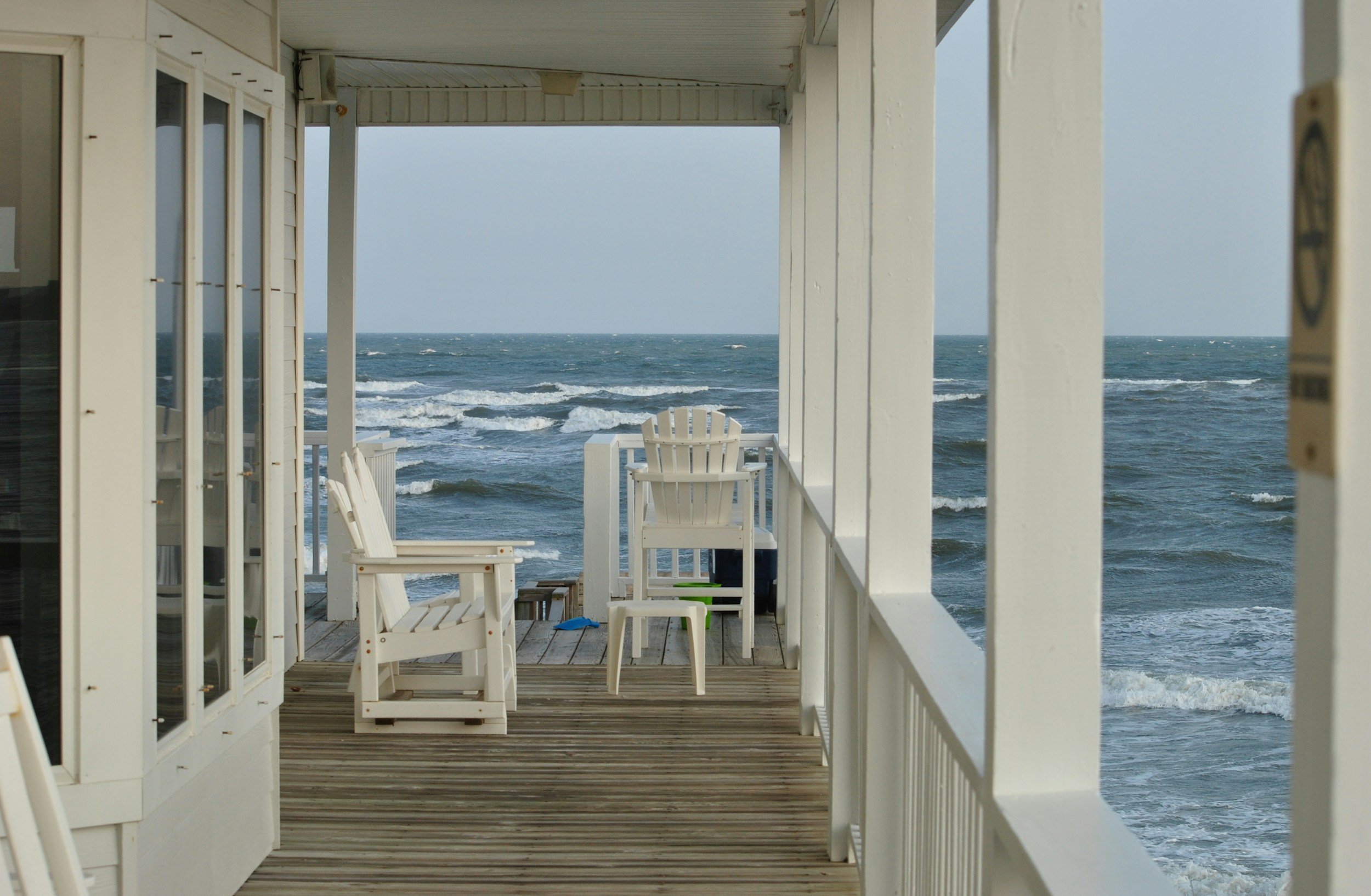 Outer Banks vacation rental home with oceanfront deck and white Adirondack chairs overlooking the beach