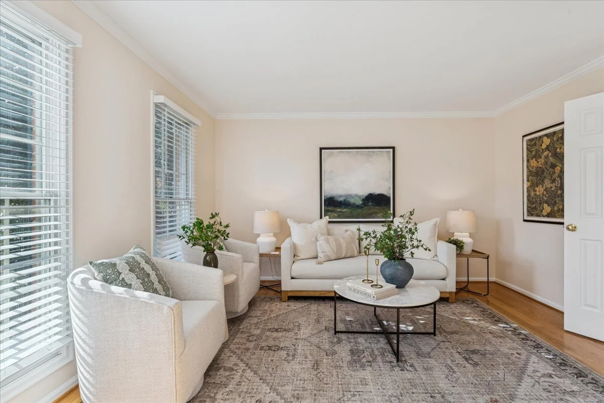 Elegant living room in a Northern Virginia home with white sofas, fireplace, and forest landscape artwork