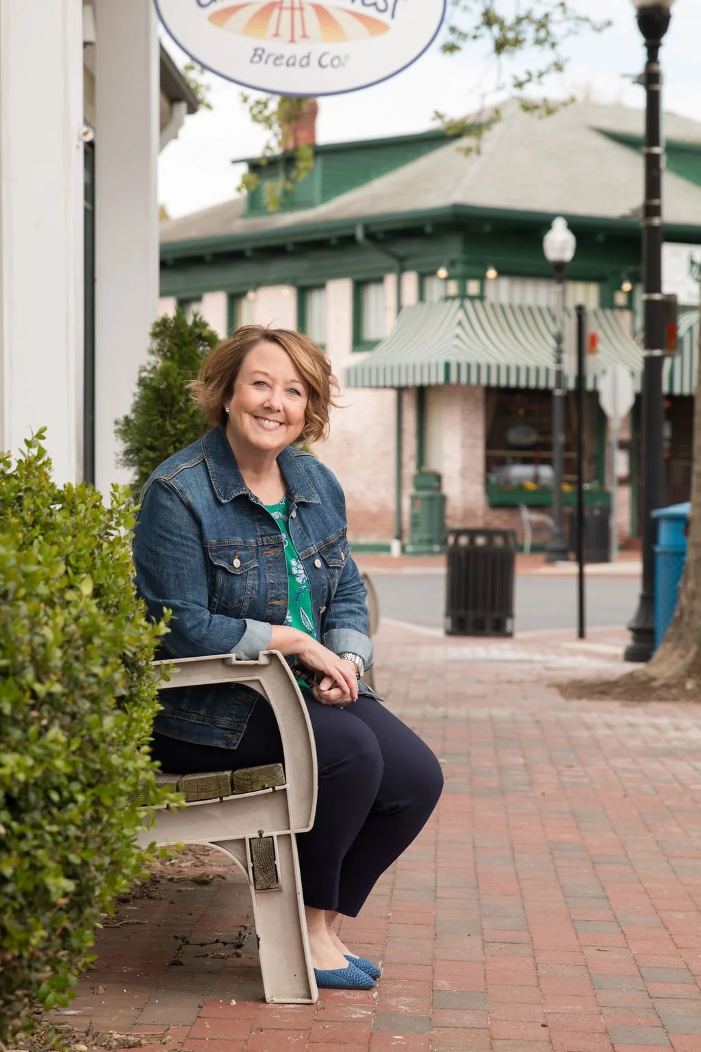 LeAnne Anies seated on a bench near shops and restaurants in Northern Virginia
