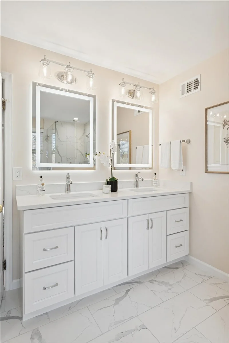 Luxury bathroom with white marble tile floors, custom vanity, and illuminated mirror in a Northern Virginia home