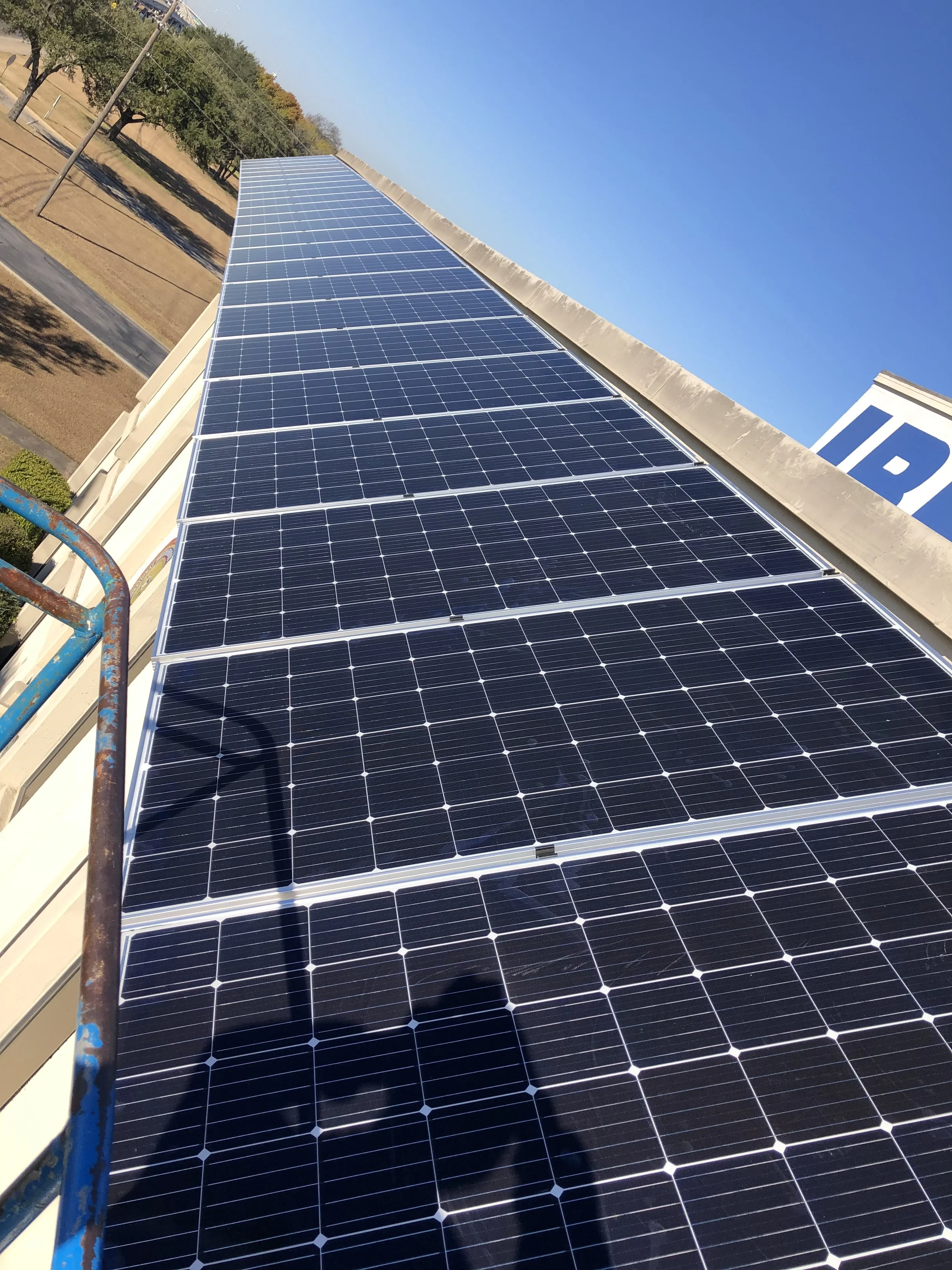 Array of solar panels installed on a rooftop under a clear blue sky.