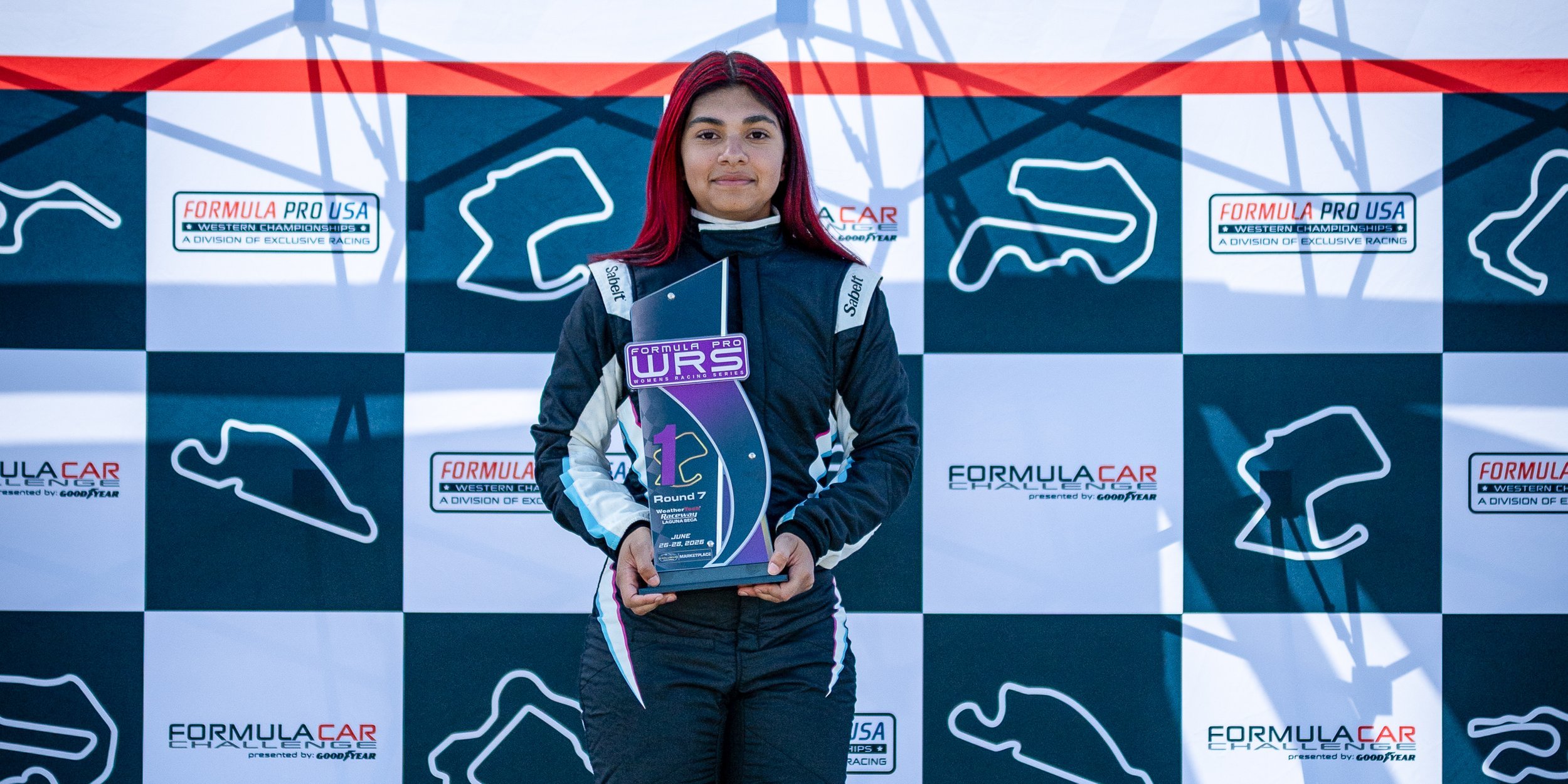 Ana Palestro holding a Formula Pro USA Women's Racing Series trophy on the podium at Laguna Seca.