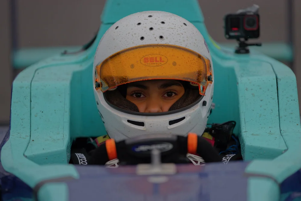 Ana Palestro in her white helmet with an orange visor, seated in her F4 car in the rain at Buttonwillow