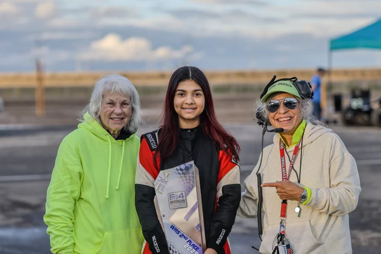 Ana Palestro holding a trophy with two supporters at the track