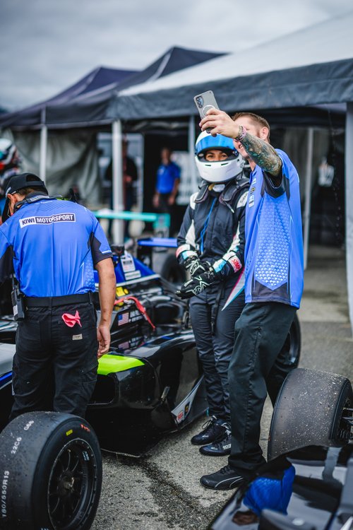 Ana Palestro in her helmet beside her Kiwi Motorsport F4 car as a supporter takes a photo, Laguna Seca, June 2026