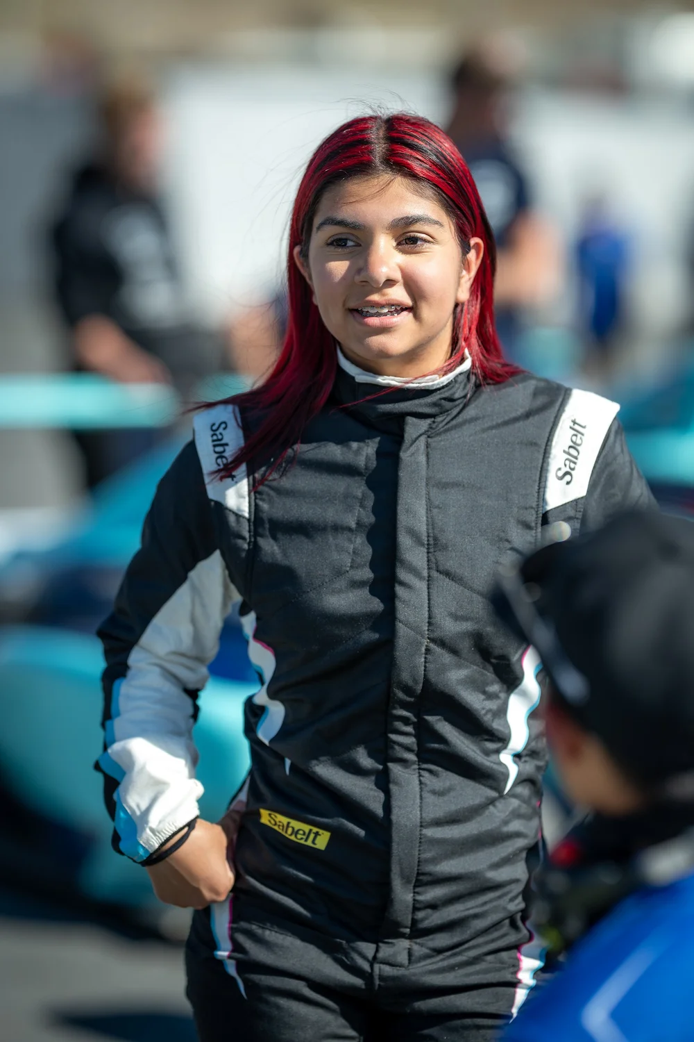 Ana Palestro walking through the paddock in her racing suit at Laguna Seca