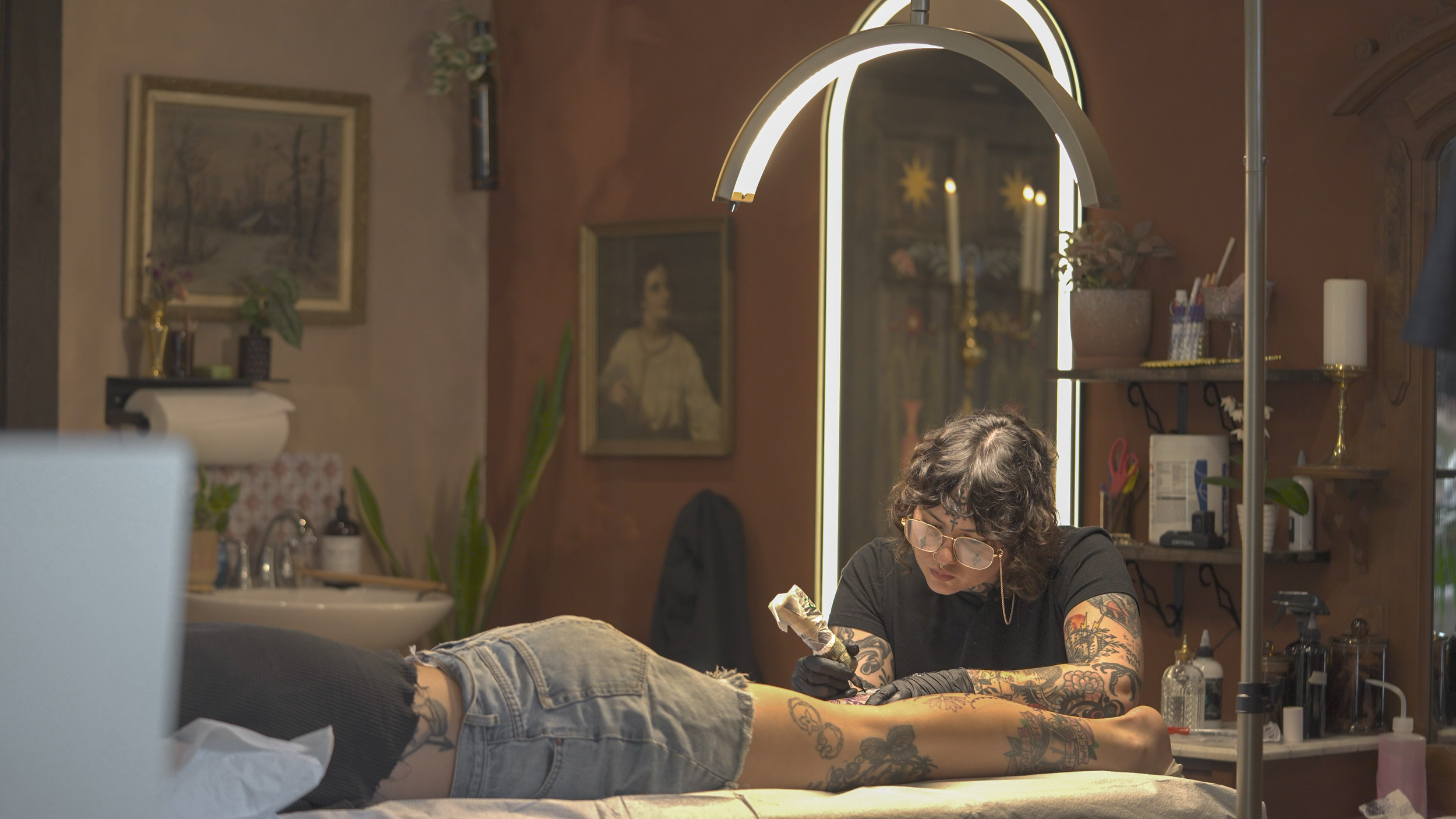Baylen Levore tattoos a client at her new studio in Asheville, N.C., on May 12, 2025. Levore relocated Pars Fortuna after her original studio on the island in Marshall was destroyed by Hurricane Helene in September 2024.