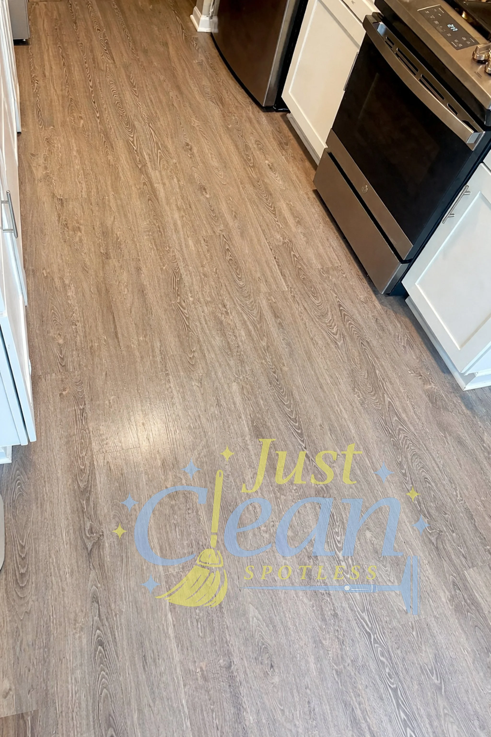 A kitchen with wooden flooring, visible appliances, and a rainbow-colored message on the floor that reads 'Just Dream & Spotless' with stars.