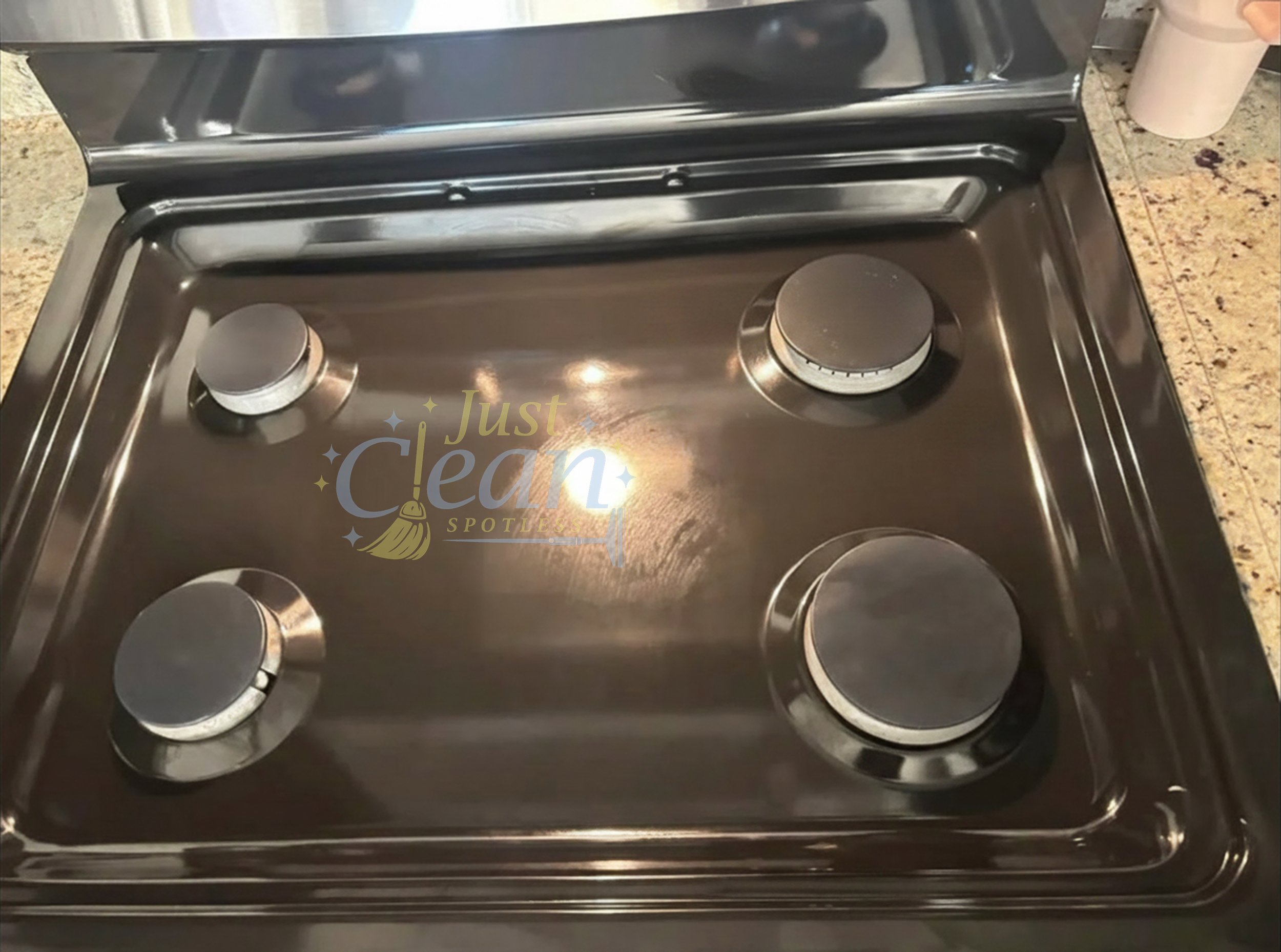 A stainless steel stovetop with four burners, two of which have heat control knobs visible, set on a kitchen countertop with a speckled granite surface.